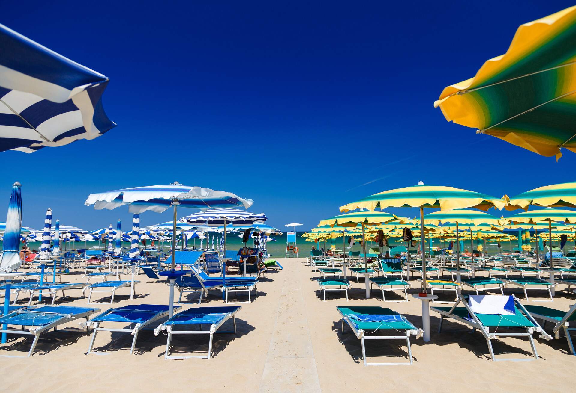 A vibrant and lively beach adorned with colourful sun beds and parasols.