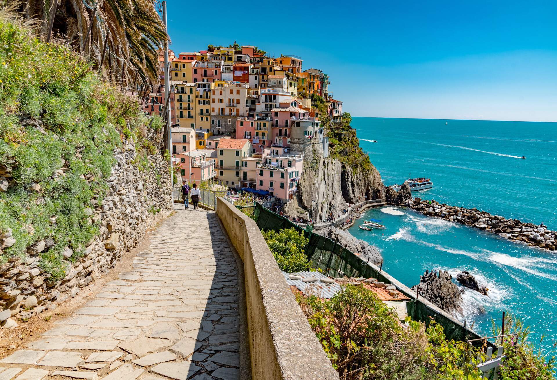 A paved downhill road by the sea overlooking the colourful traditional hillside houses.