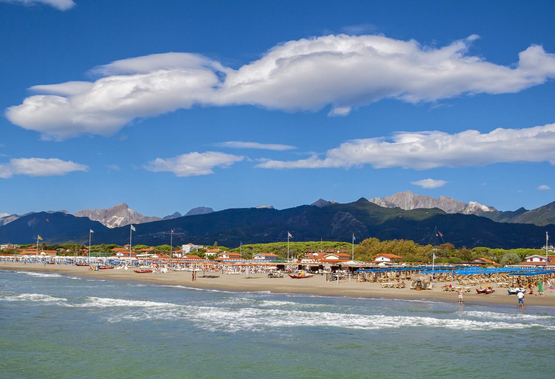 A beach with rows of sunbeds, umbrellas, and picnic tents.