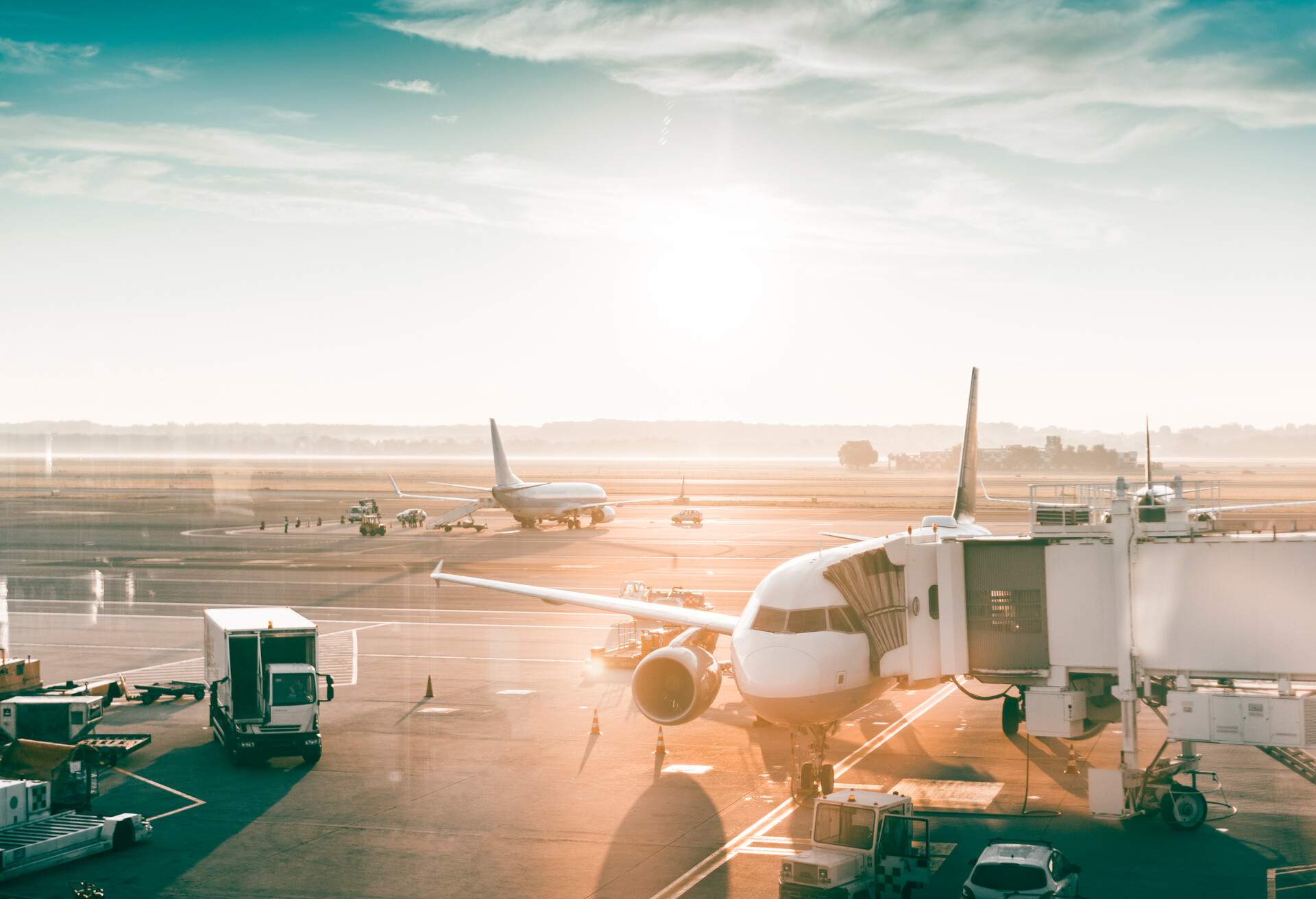 A busy runway full of tow trucks and airplanes connected to skybridges.