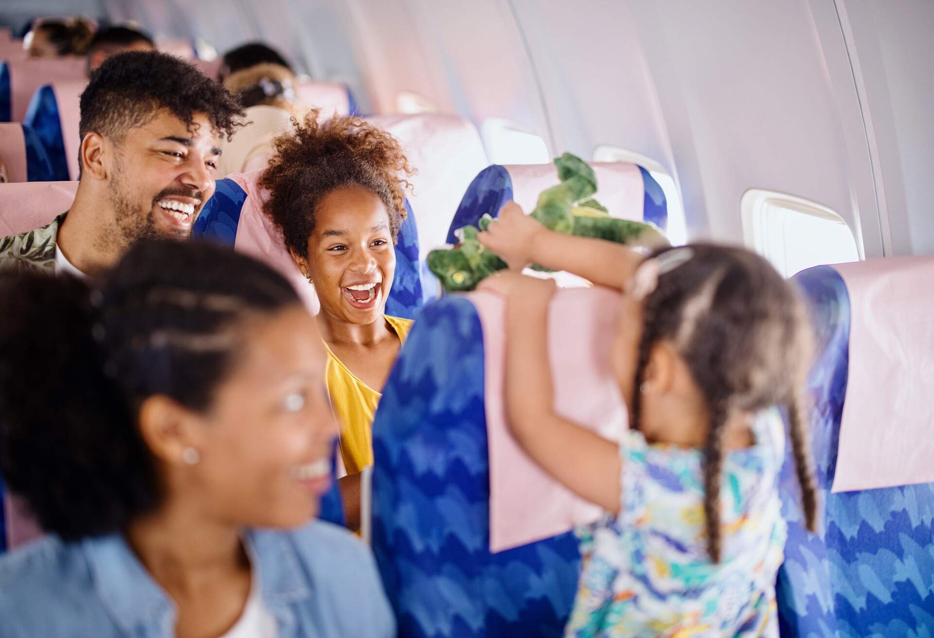 A happy family with a child sits inside an aeroplane.