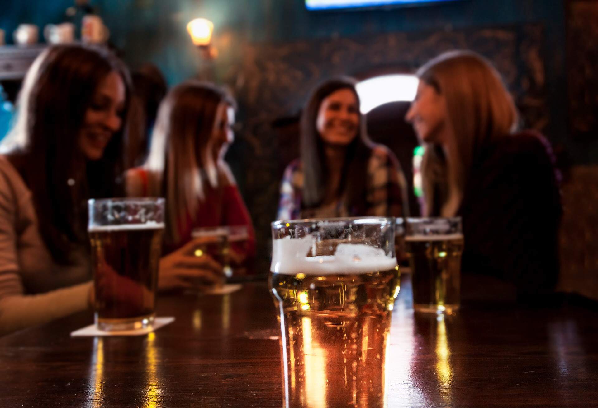Group of millennial women having fun drinking beer in a pub.