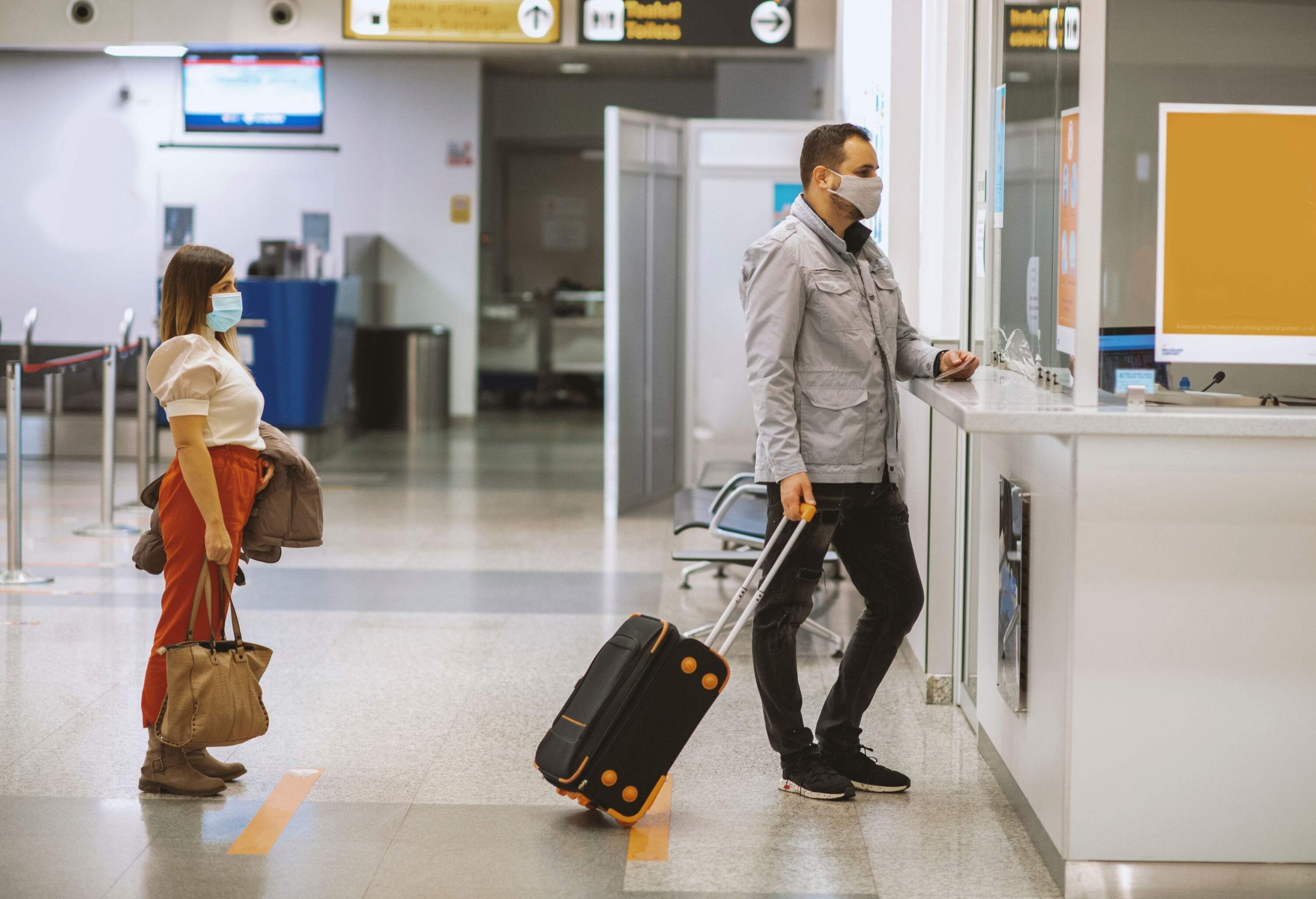 Passengers wearing face masks checking in for their flight at an airport.