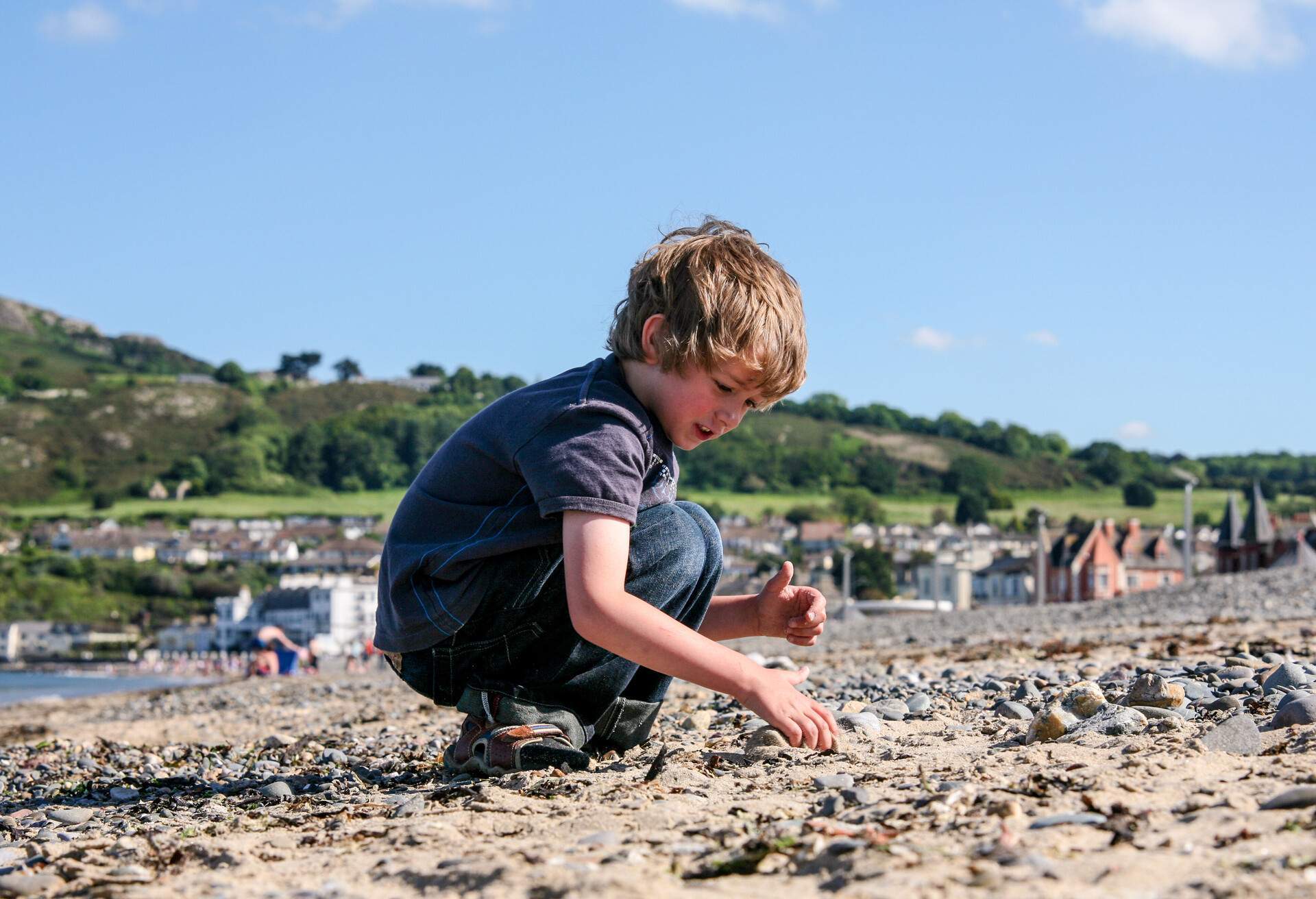 Young Boy Picking Stones on a Beach, Bray, Ireland.