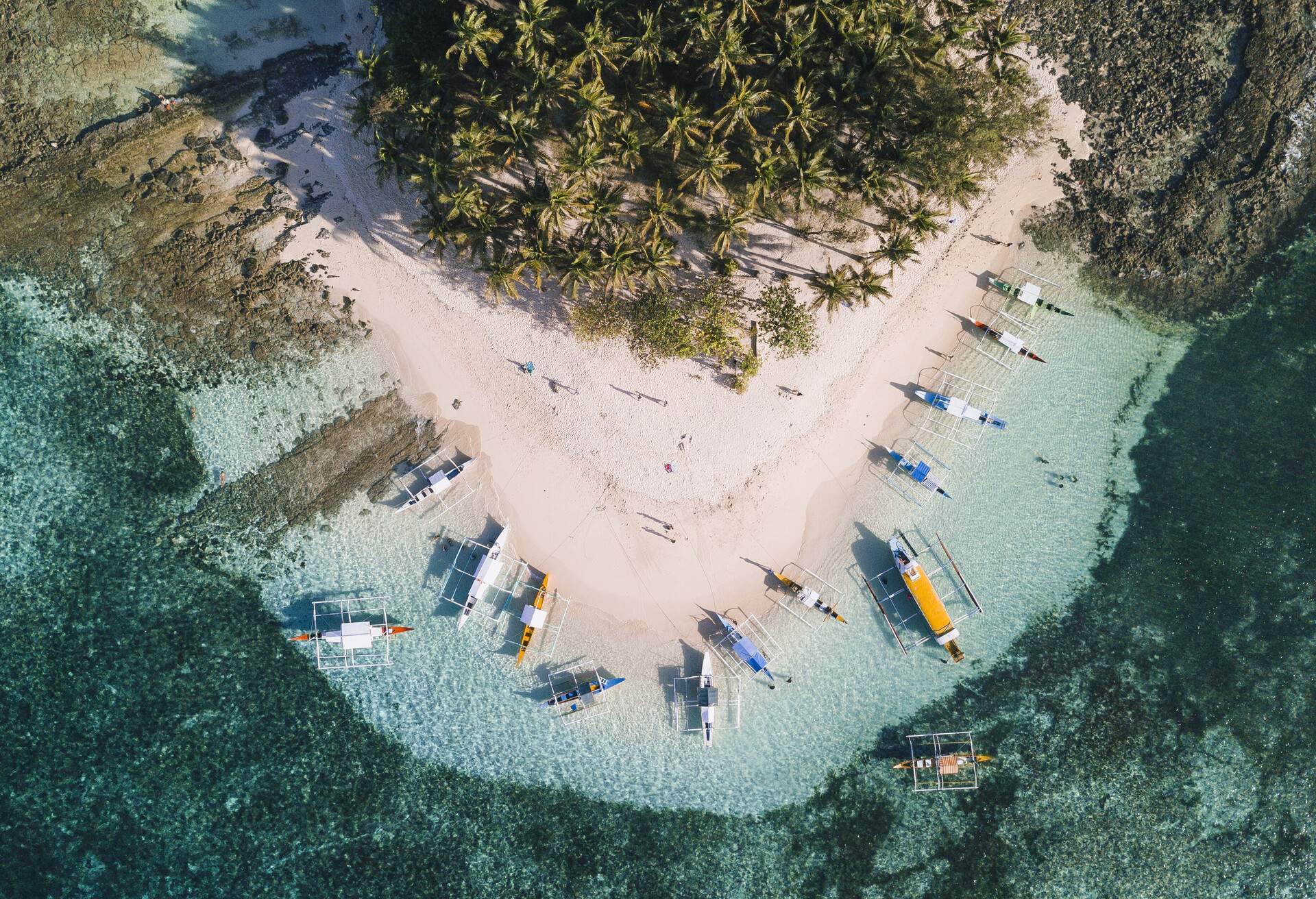 Drone view of Siargao island with palm trees on beach surrounded by boats, Philippines