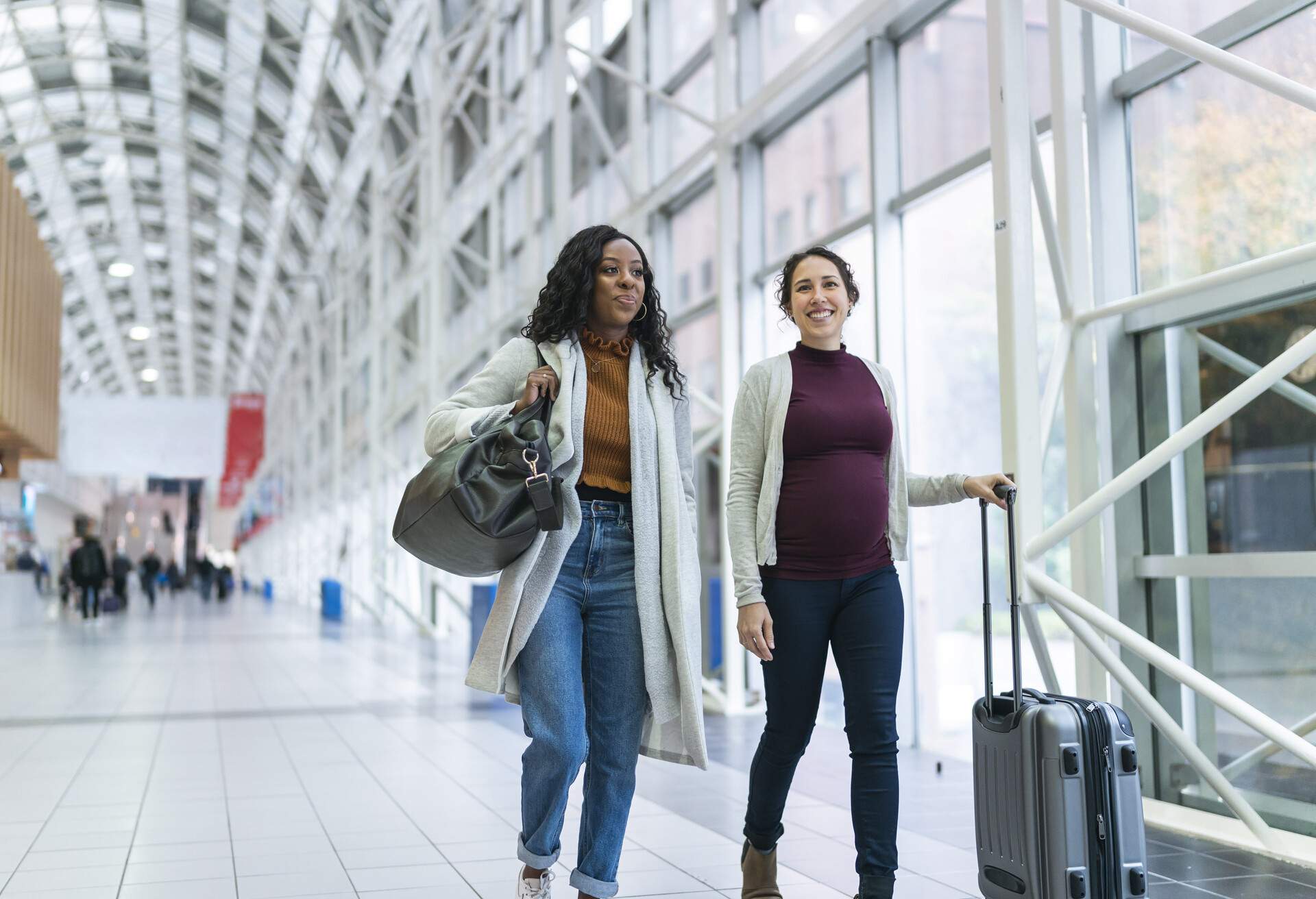 Women at an airport walking with their luggage