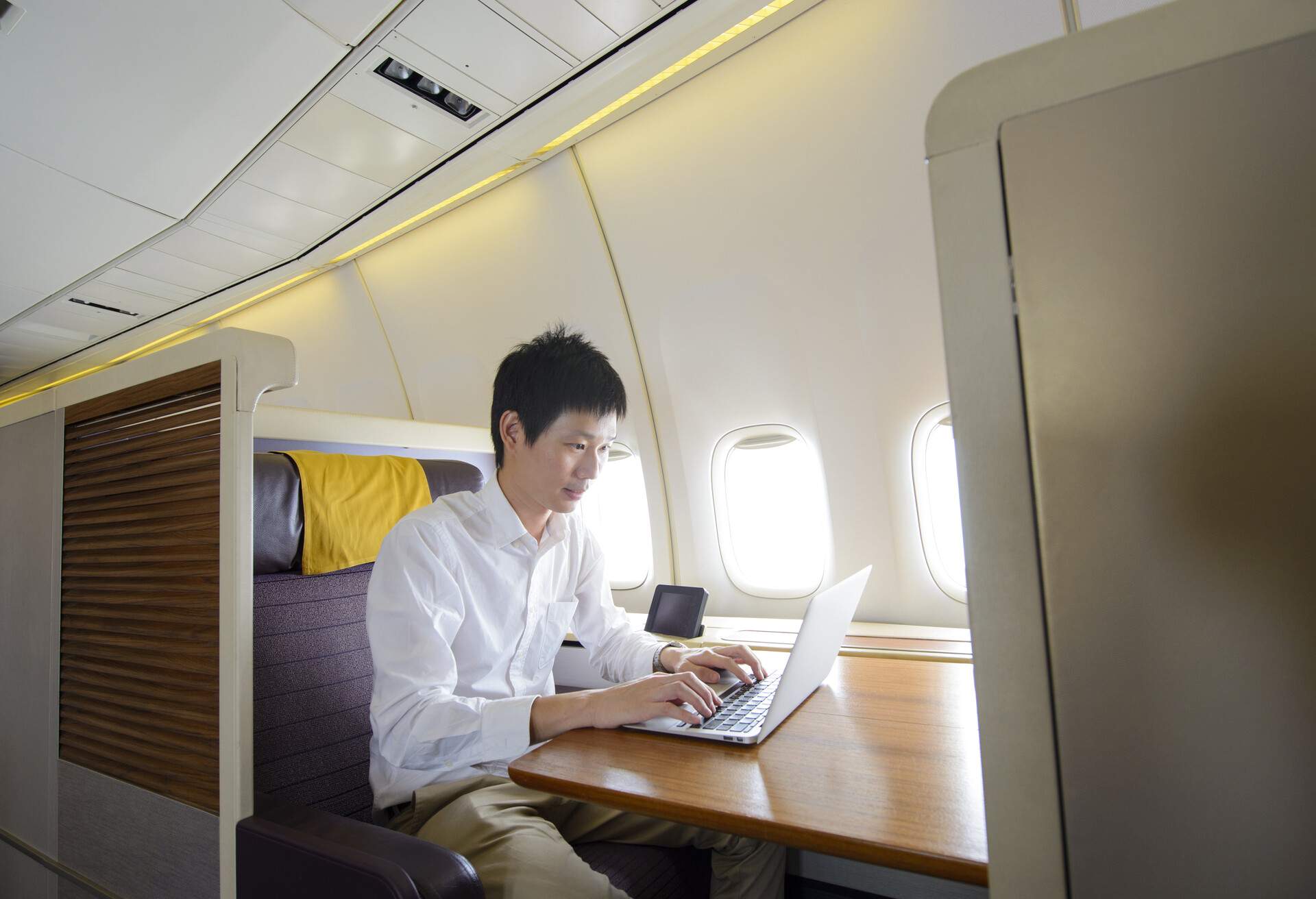 Man working on laptop on a business class flight