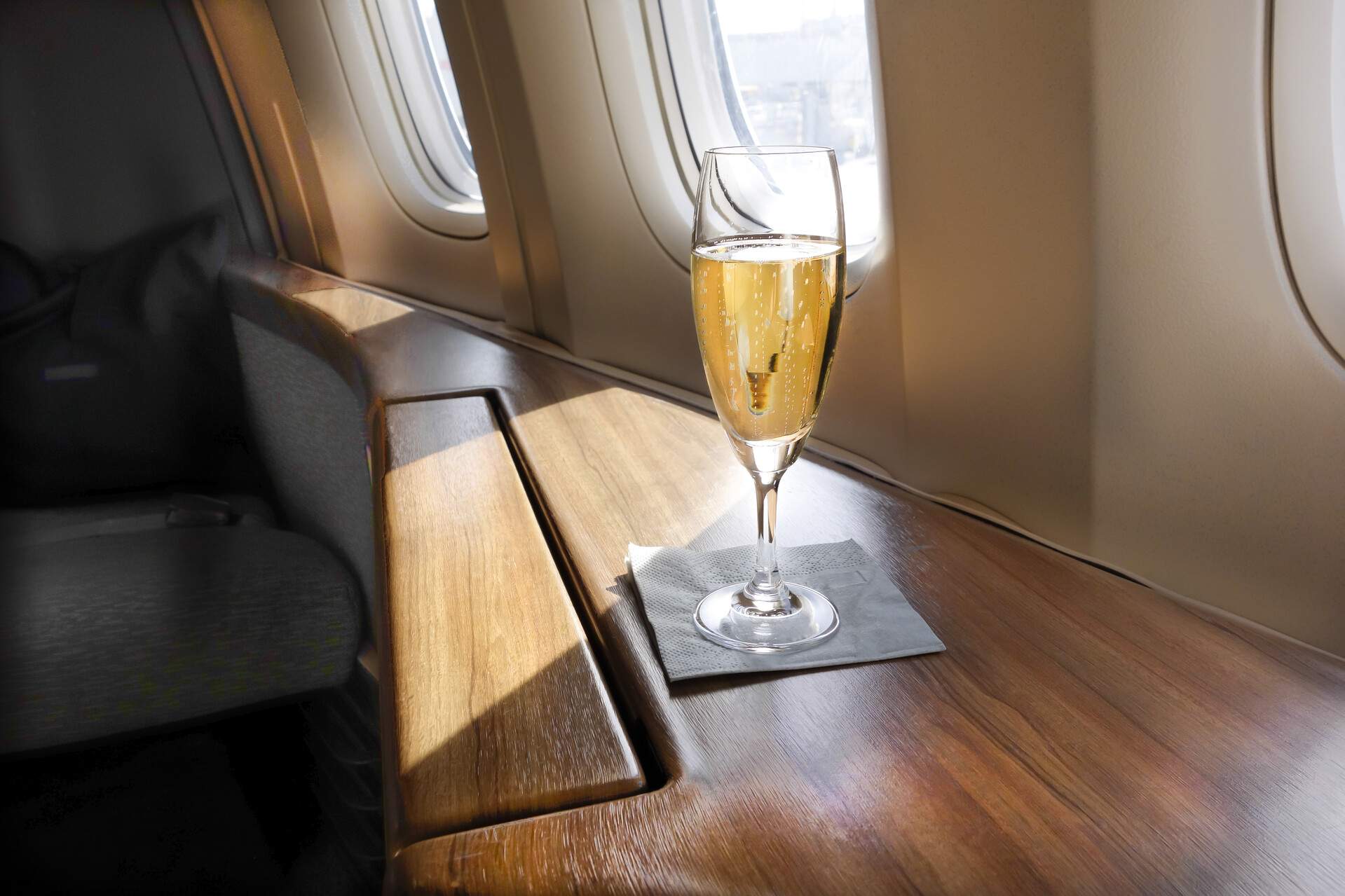 A glass of exquisite champagne awaits a privileged first-class passenger, ready to be savoured during their luxurious airline journey.