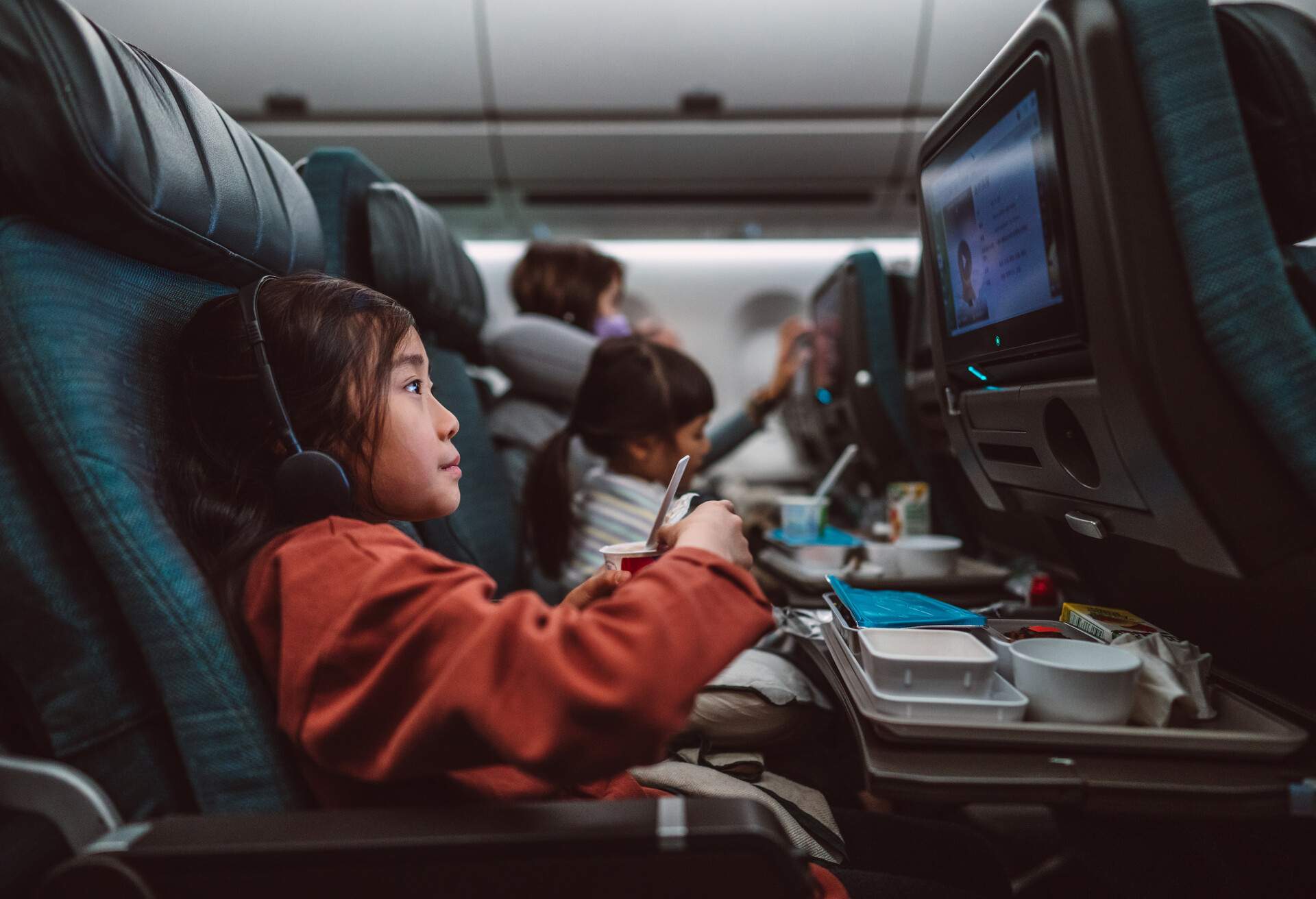 Child on plane watching a movie with food tray
