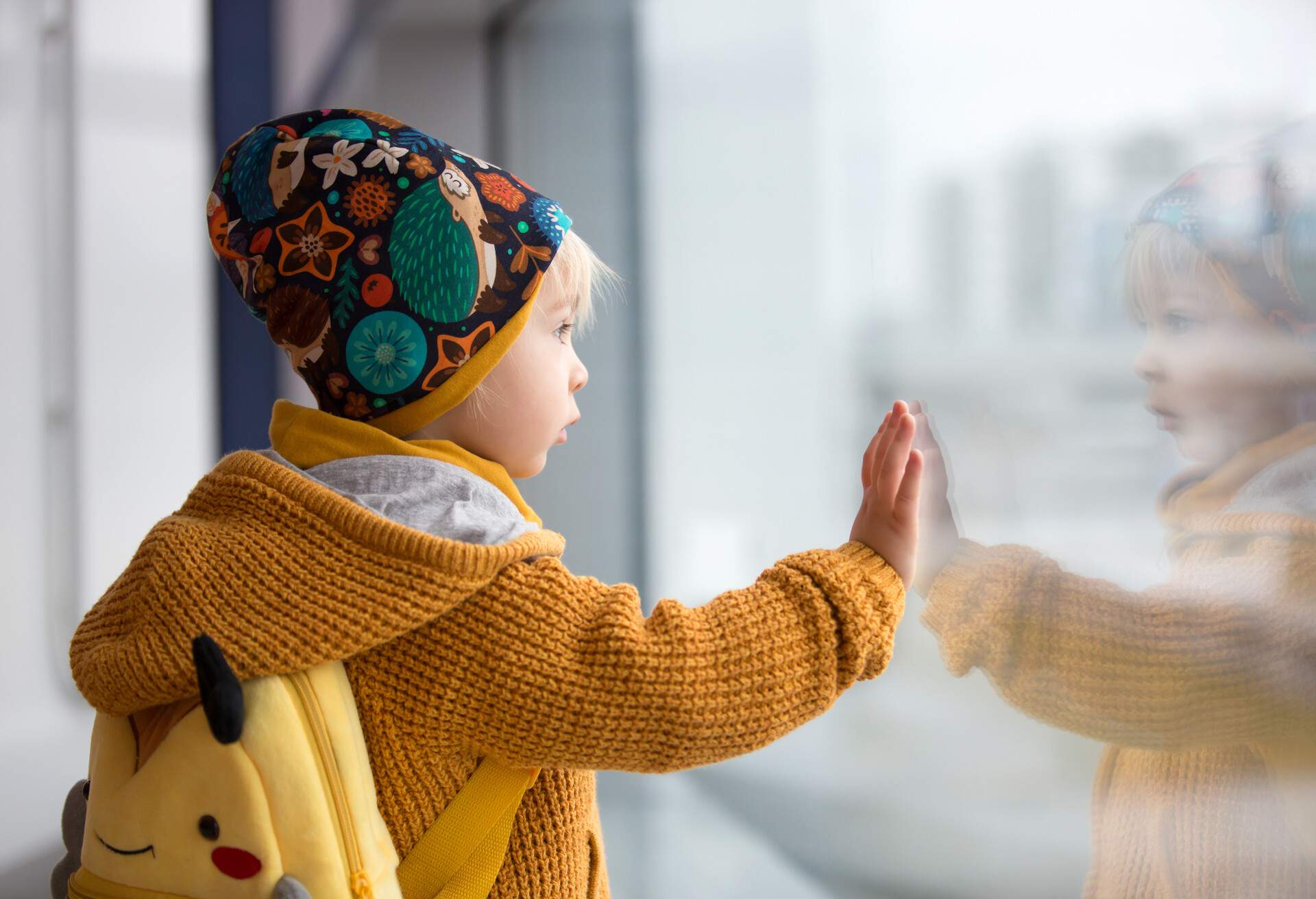 Blond toddler boy with family, traveling with airplane, running at the airport with suitcase.