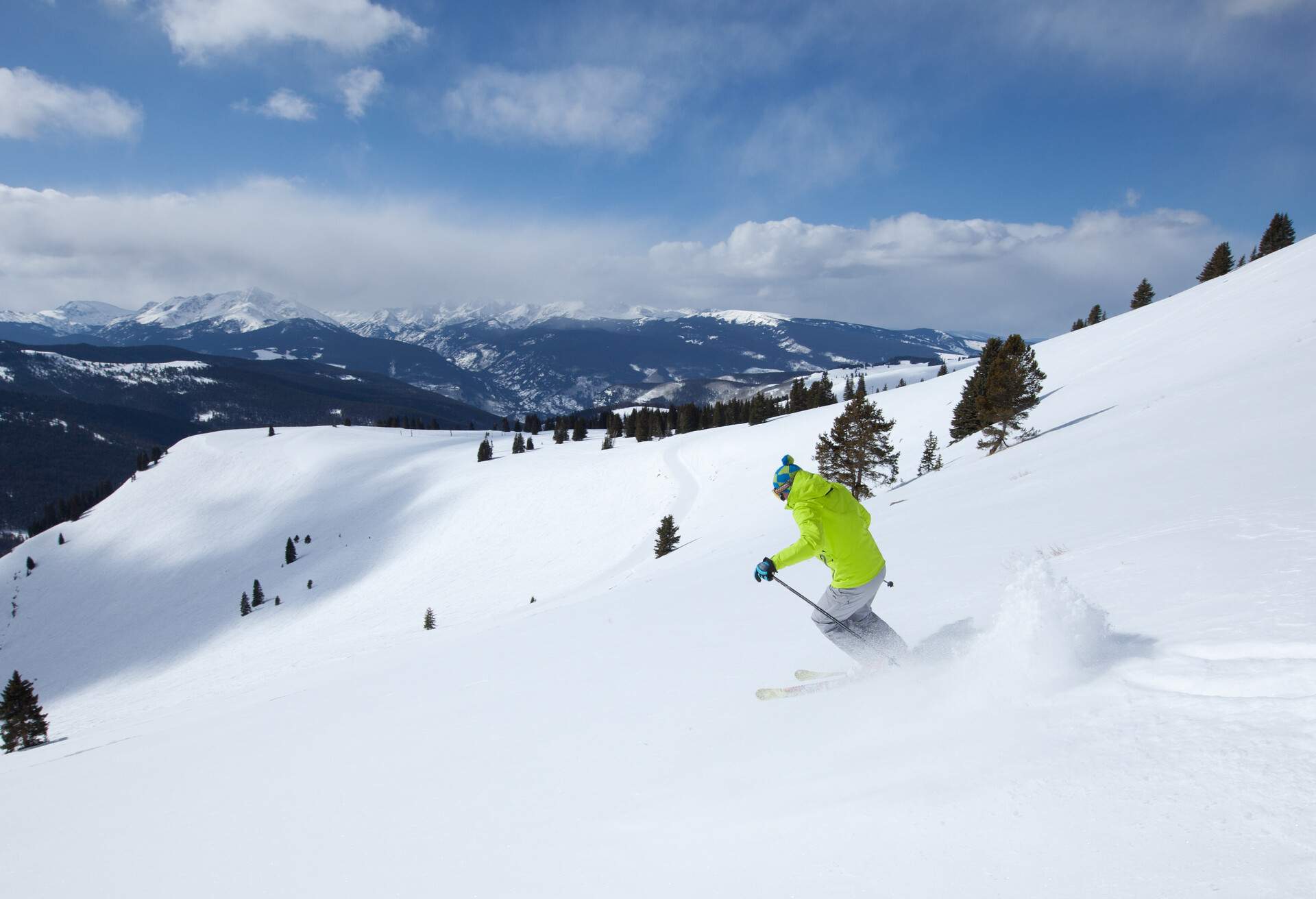 A skier descends a powder snow land of a mountain covered in snow.