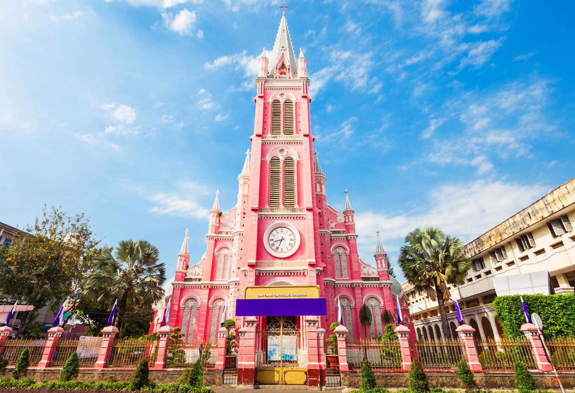 A unique church painted in pastel pink with a central clock tower protruding into the sky.