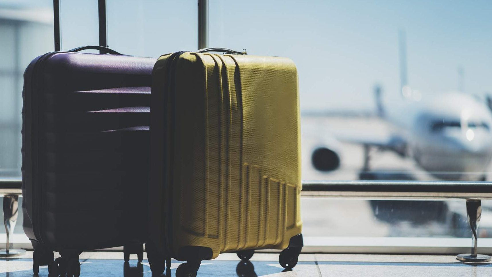 Portrait of two spinner luggage in an airport lounge.