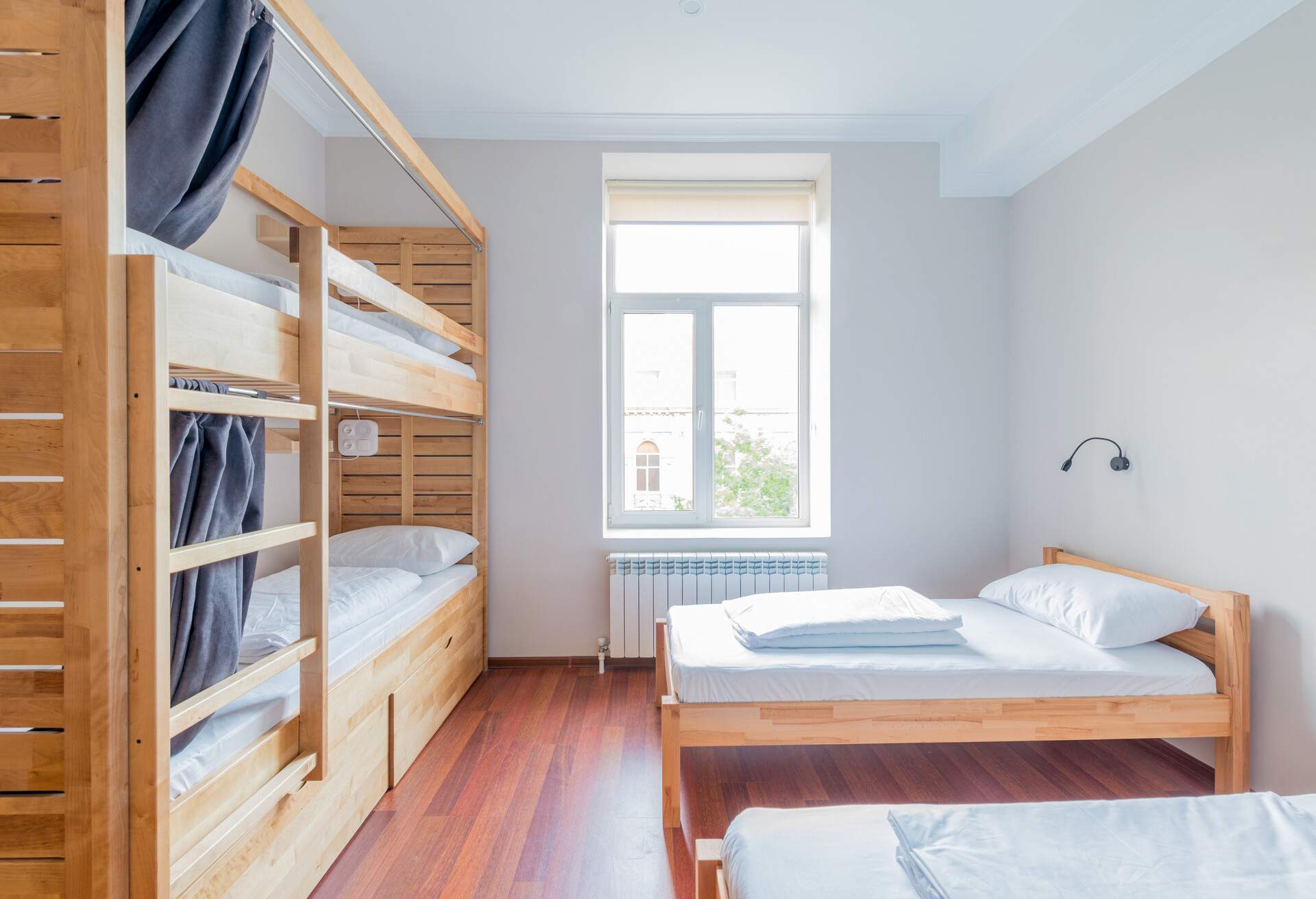A hostel room with a bunk bed and twin beds.