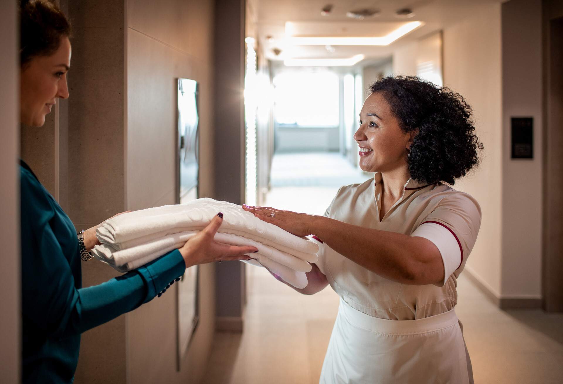 Close up of a maid changing the towels for a young lady staying at the hotel.