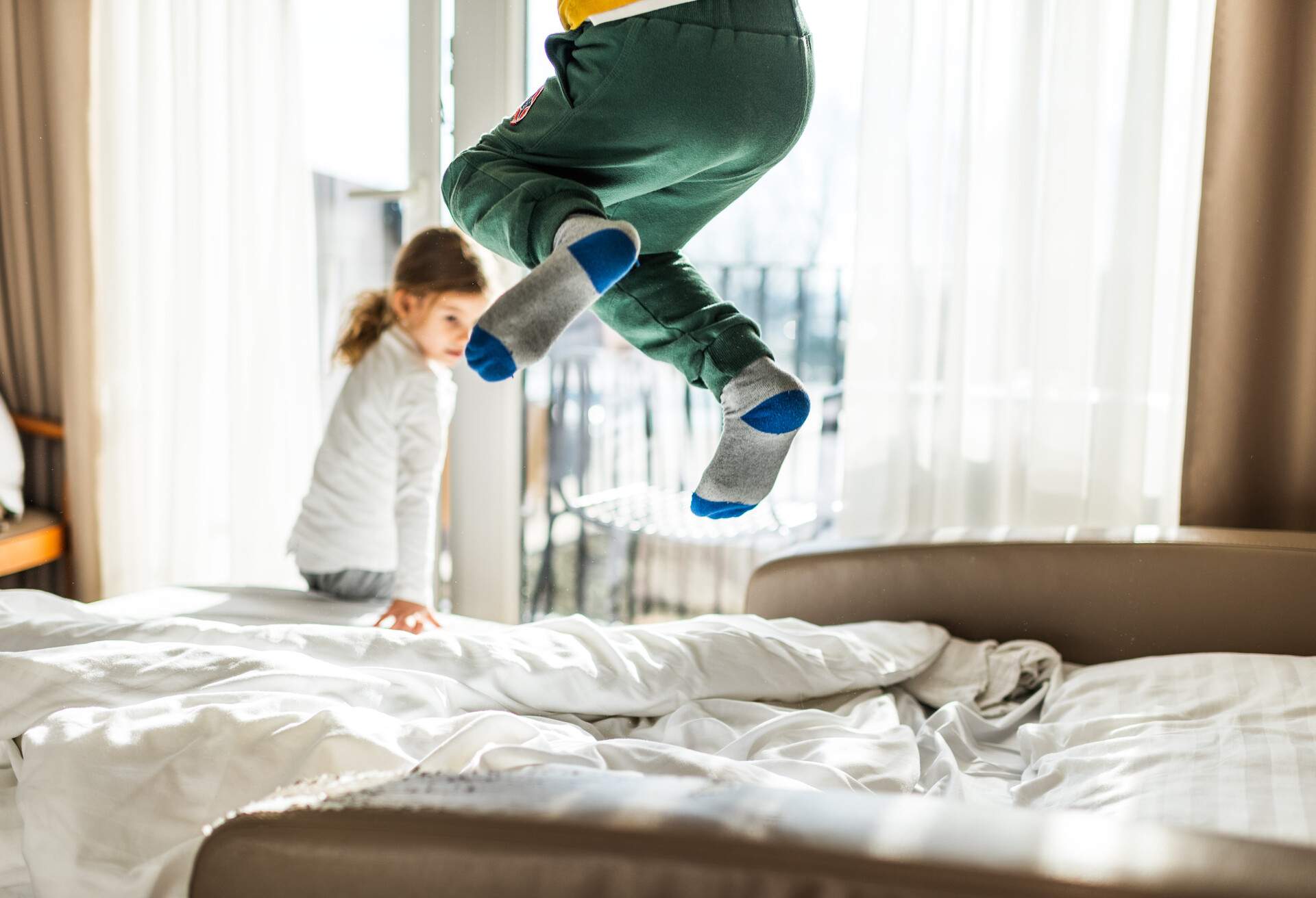 A young child with socks on jumping on the bed.