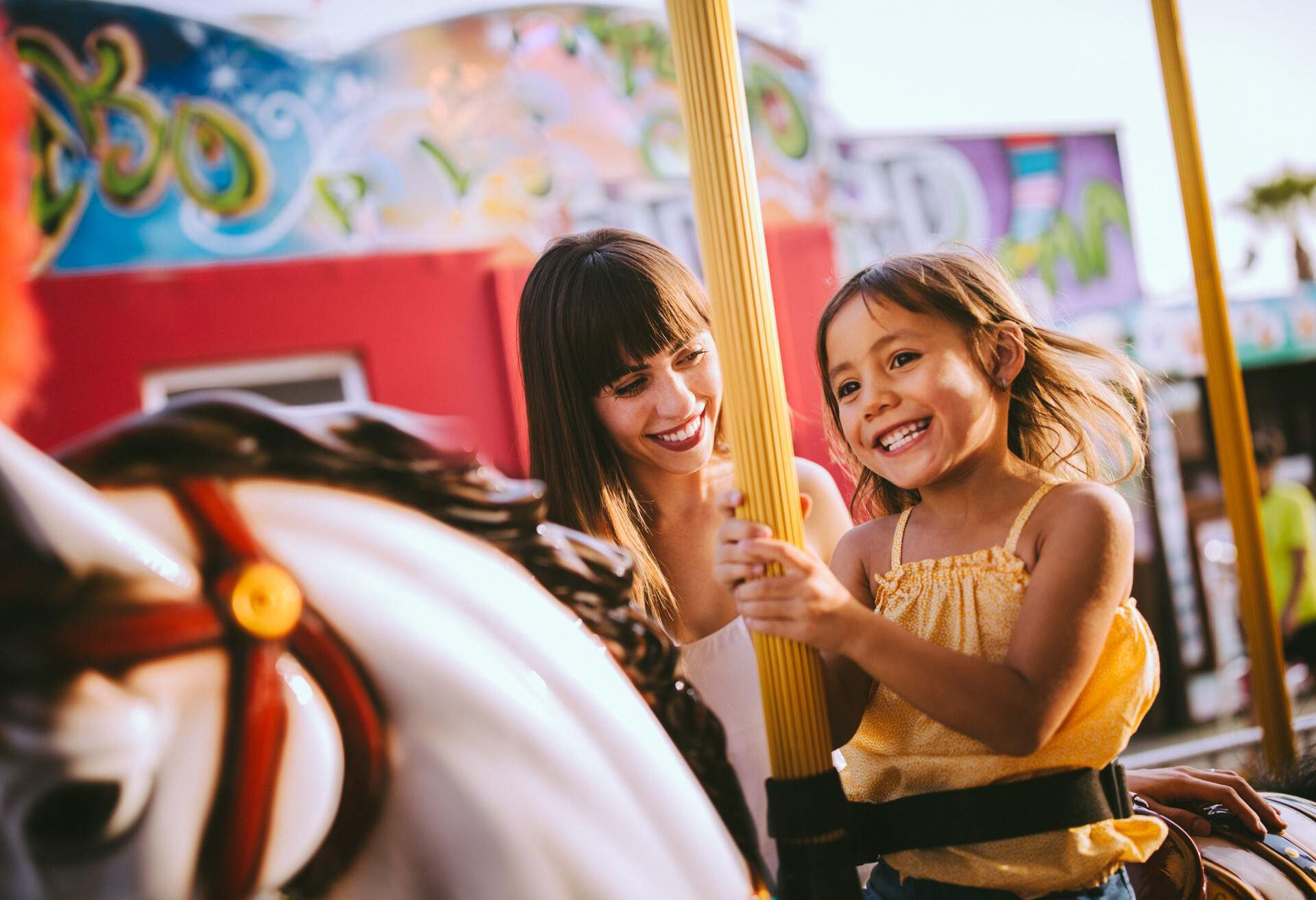 A little girl smiling at a theme park with her mum