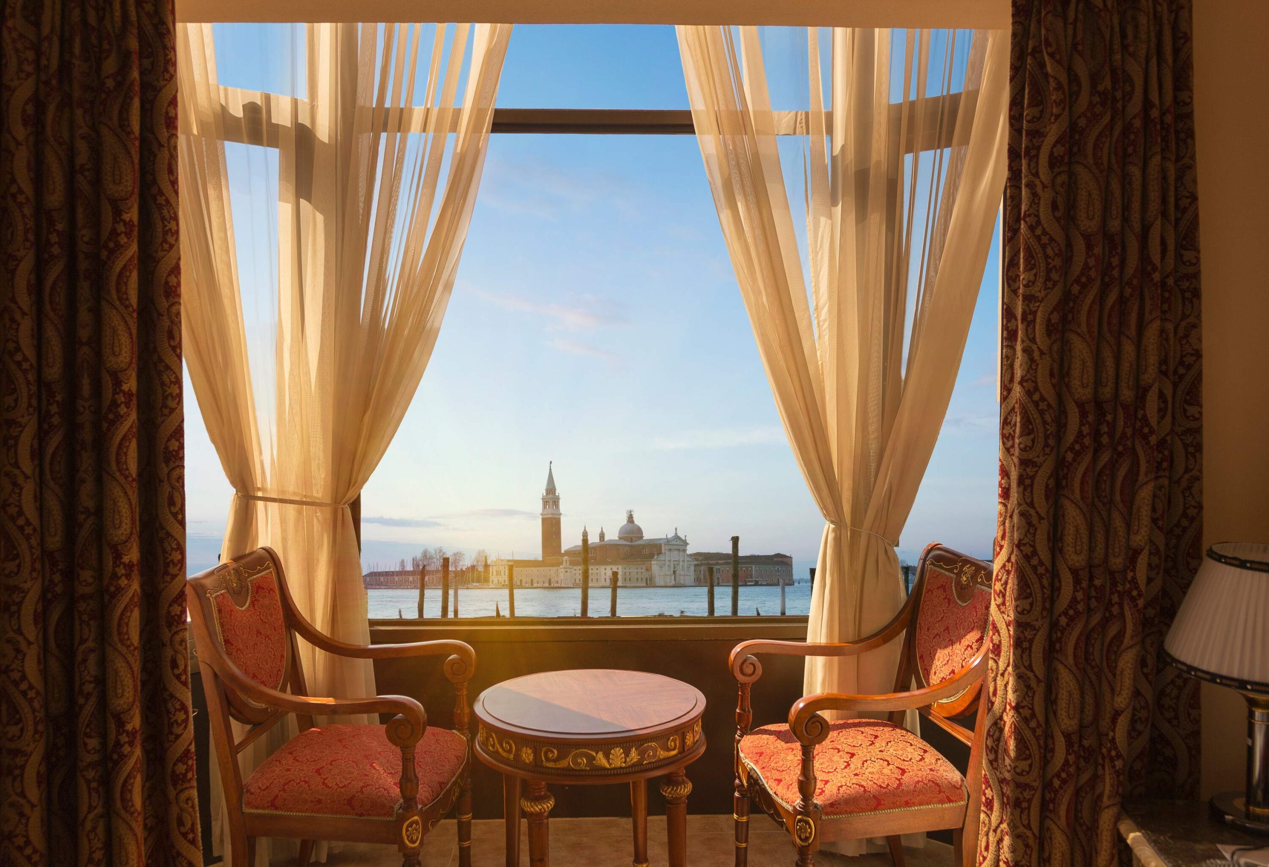 View of Venice laguna from luxury hotel with chairs and curtains in foreground