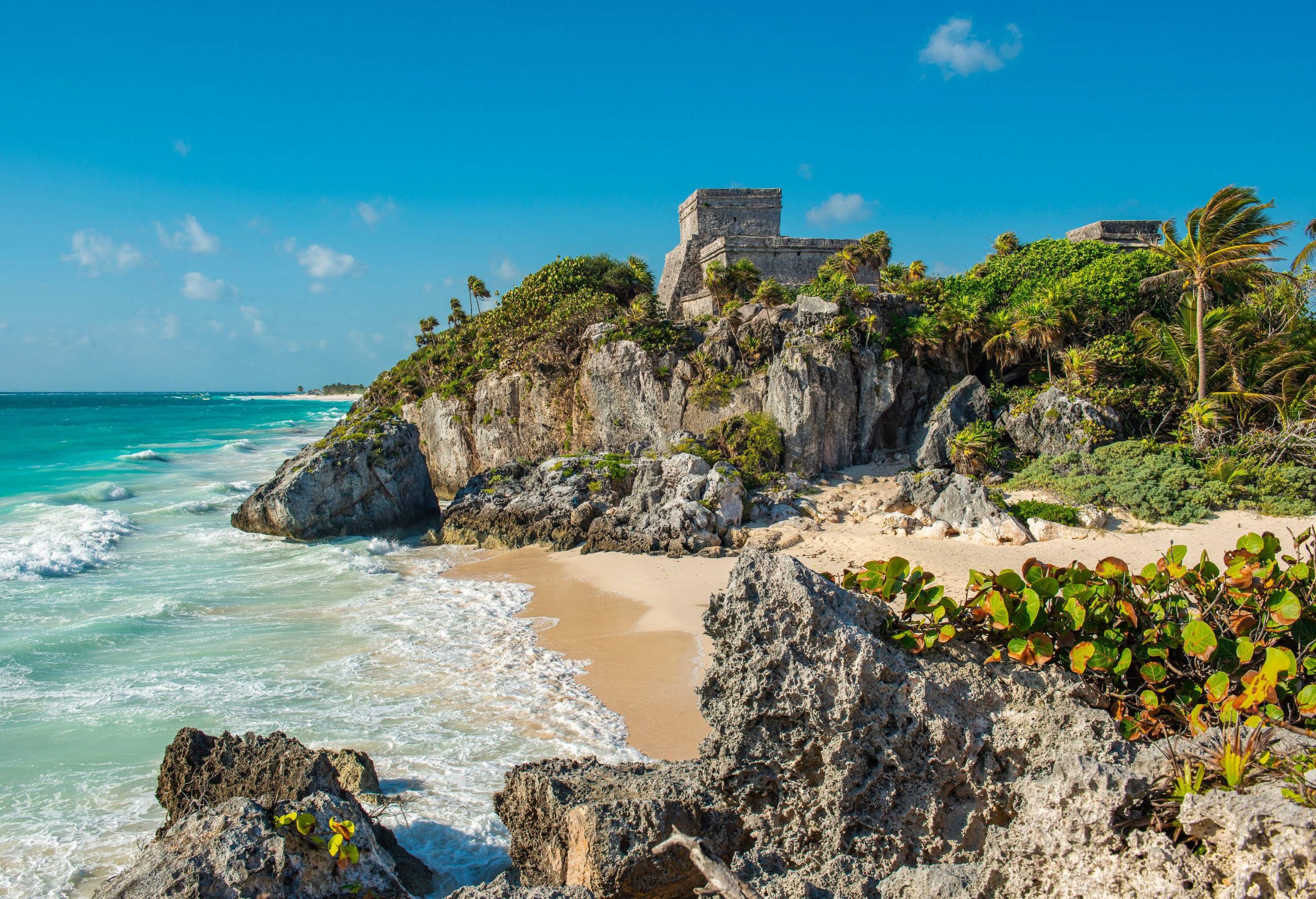 A rocky island with a sandy shore by the wavy beach.