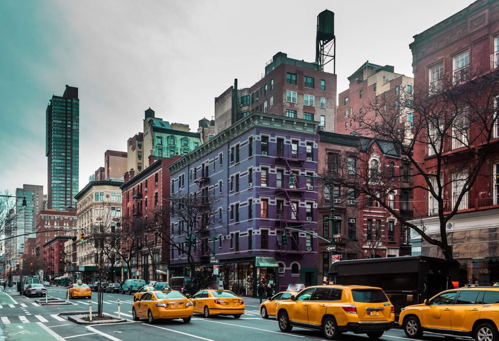 A bustling street with yellow cabs and cars lined with colourful buildings.