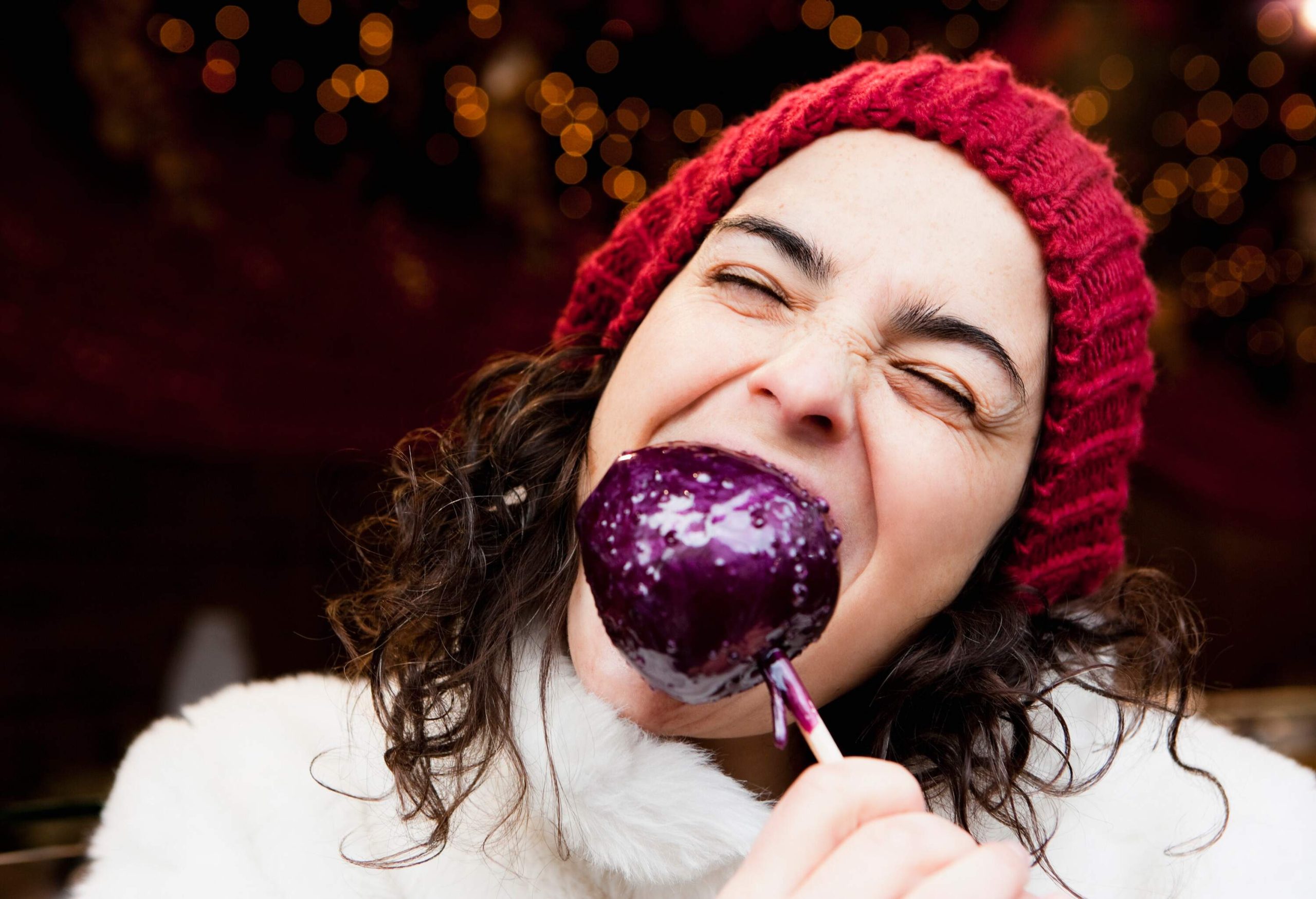 Woman taking a bite of candied apple.