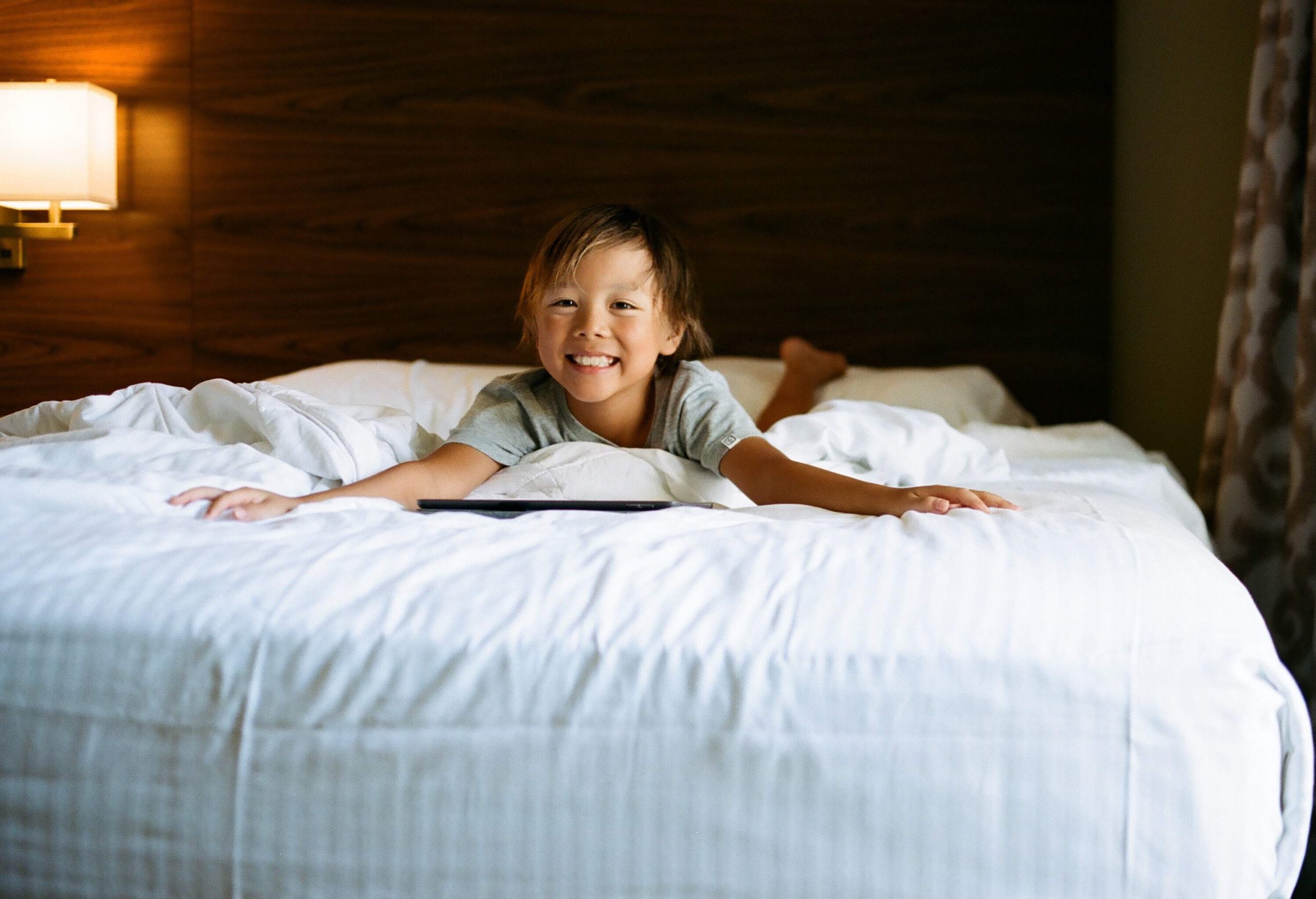 A young boy laying on his stomach on a large bed.