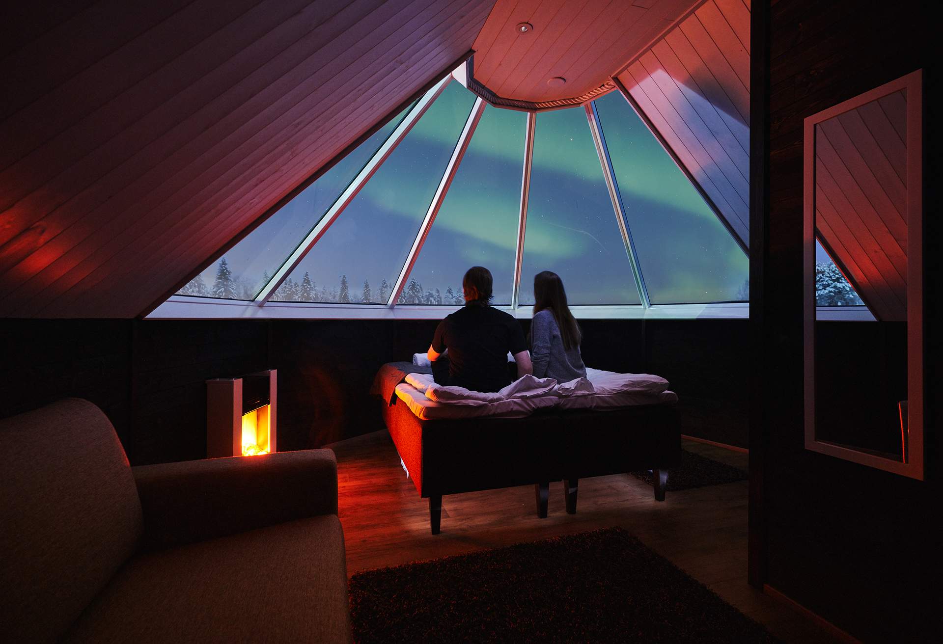 Couple looking at aurora borealis from igloo cabin