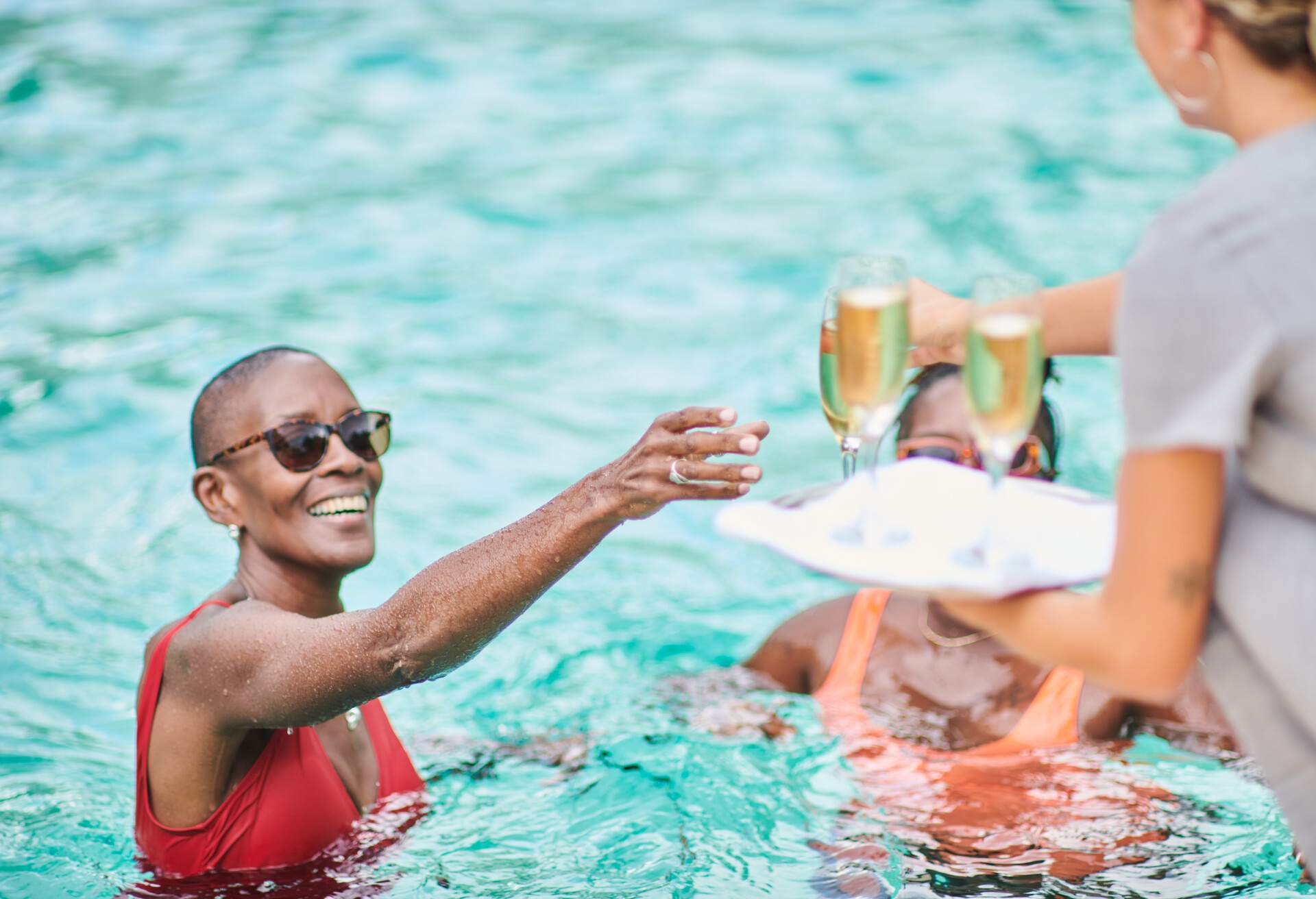 Server bringing champagne flutes to guest at the pool