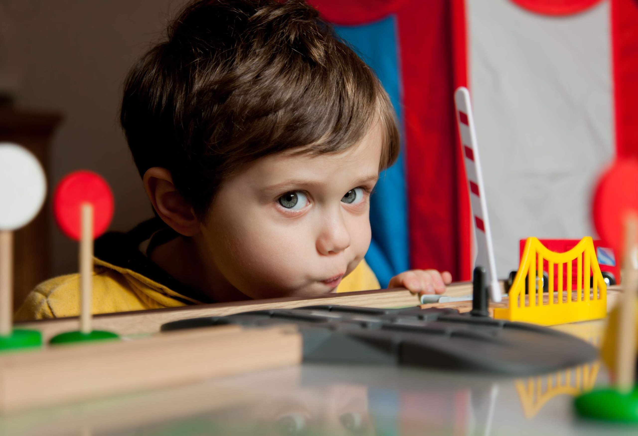 A little boy plays with train toys.