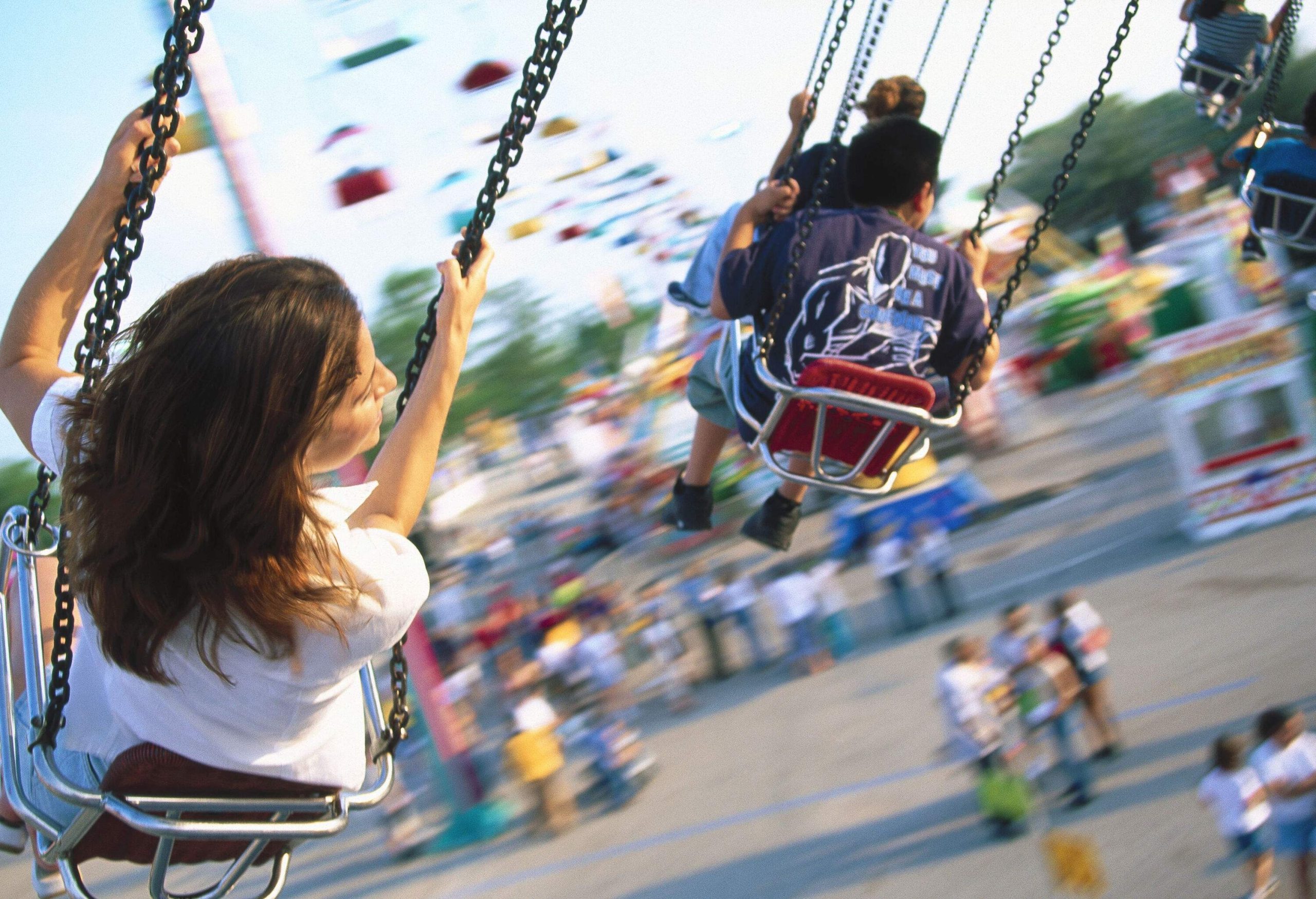 Children and adults riding a swing carousel at an amusement park.