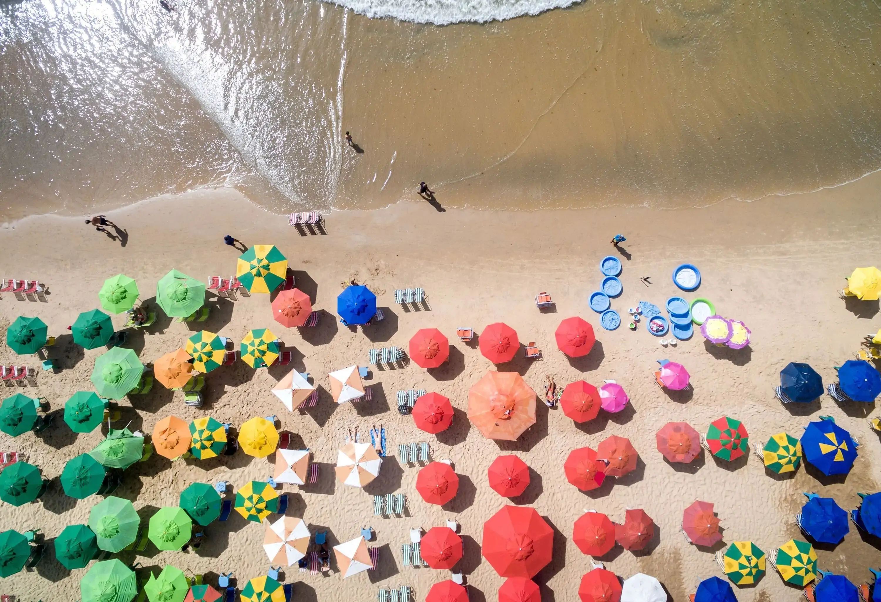 Beach umbrellas in various colours and patterns across the sand.