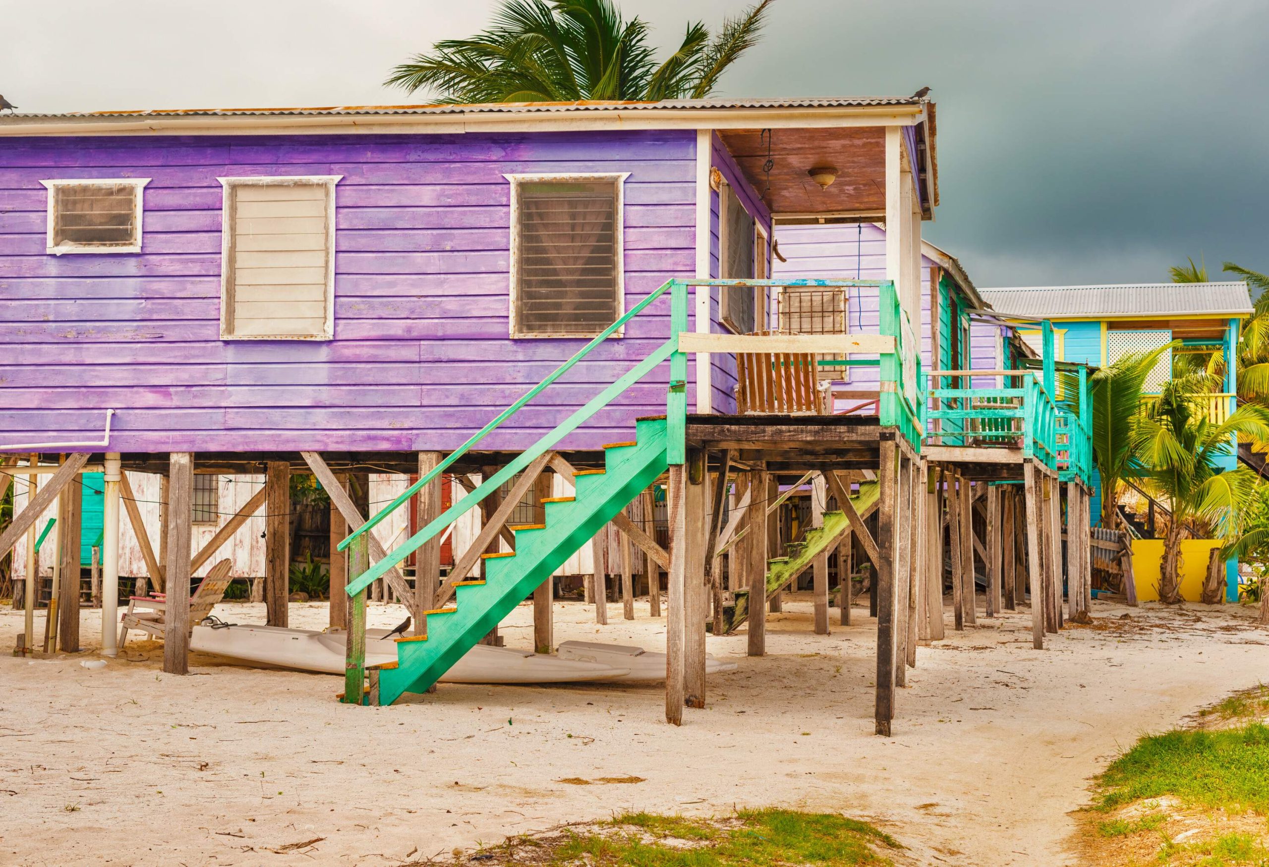 Colourful wooden houses raised on stilts over the sandy ground.