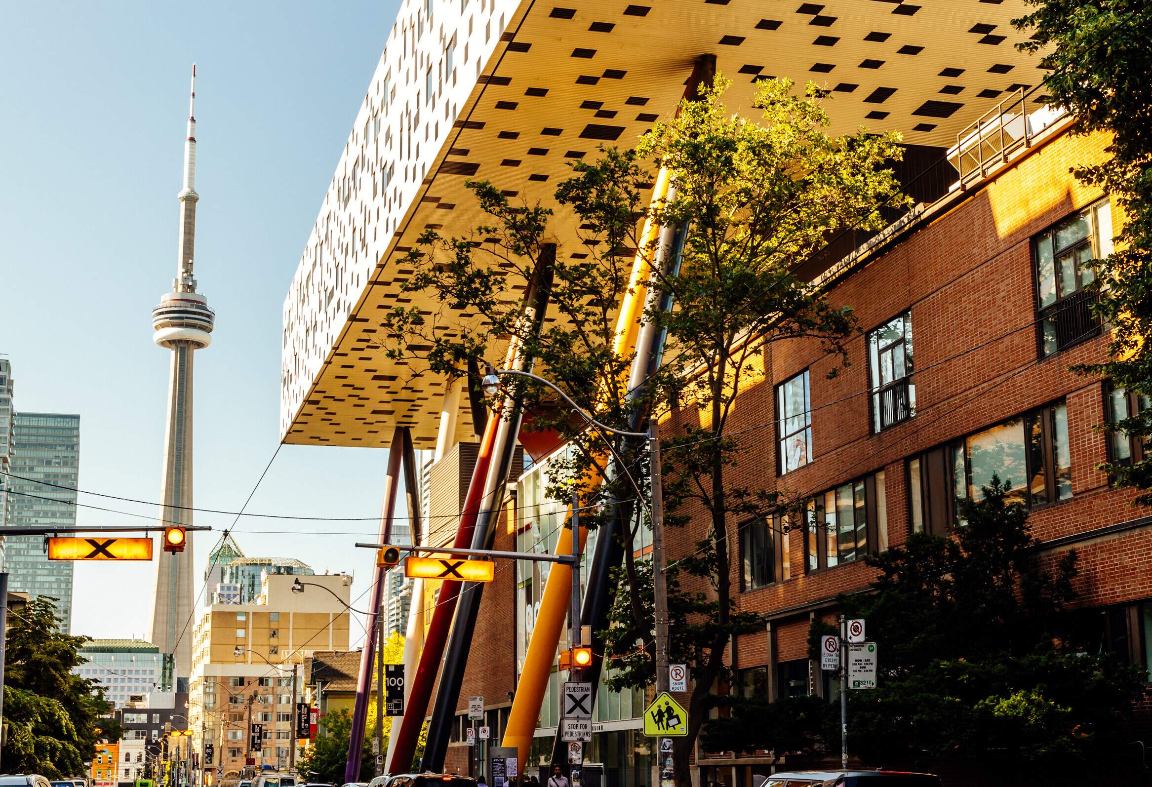 The CN Tower and the unique main building of OCAD University tower over Toronto's downtown street.