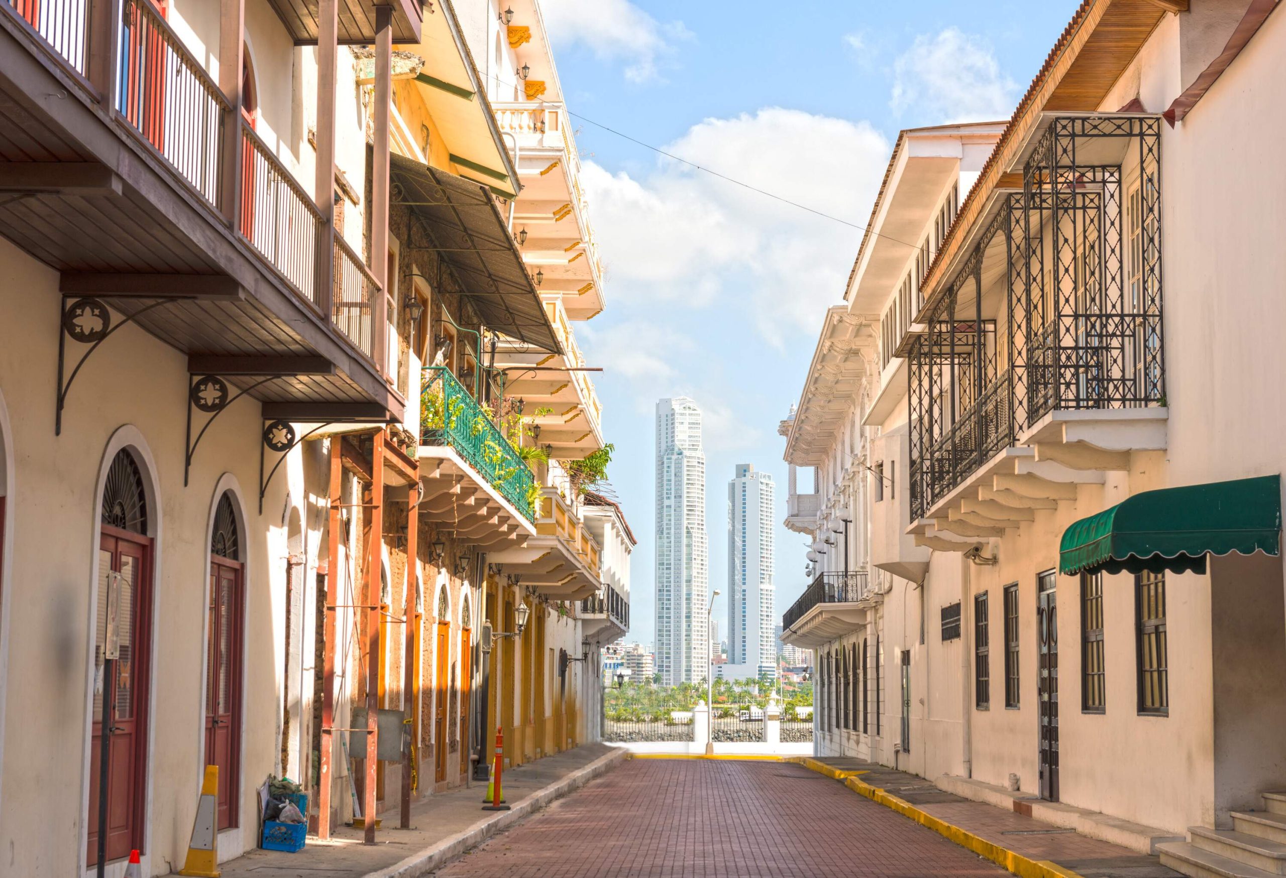 An empty paved alleyway with a view of towering buildings in the distance.