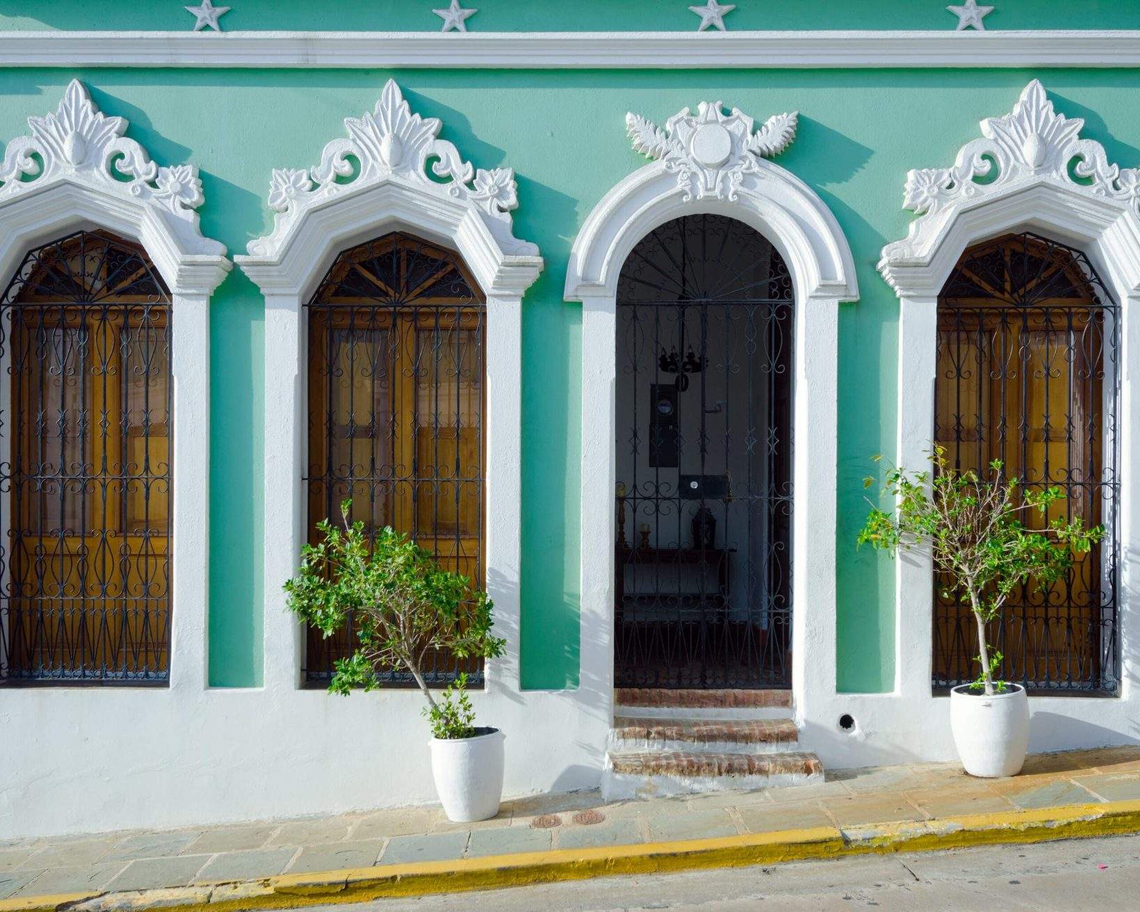 A building with light green exterior walls and white arched mouldings around its windows and doorway.