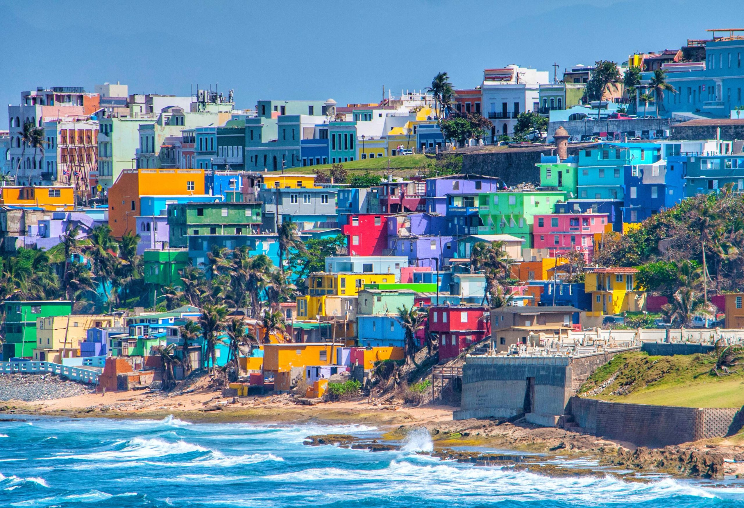 A bright cityscape with multicoloured residences on the slopes by the sea. 