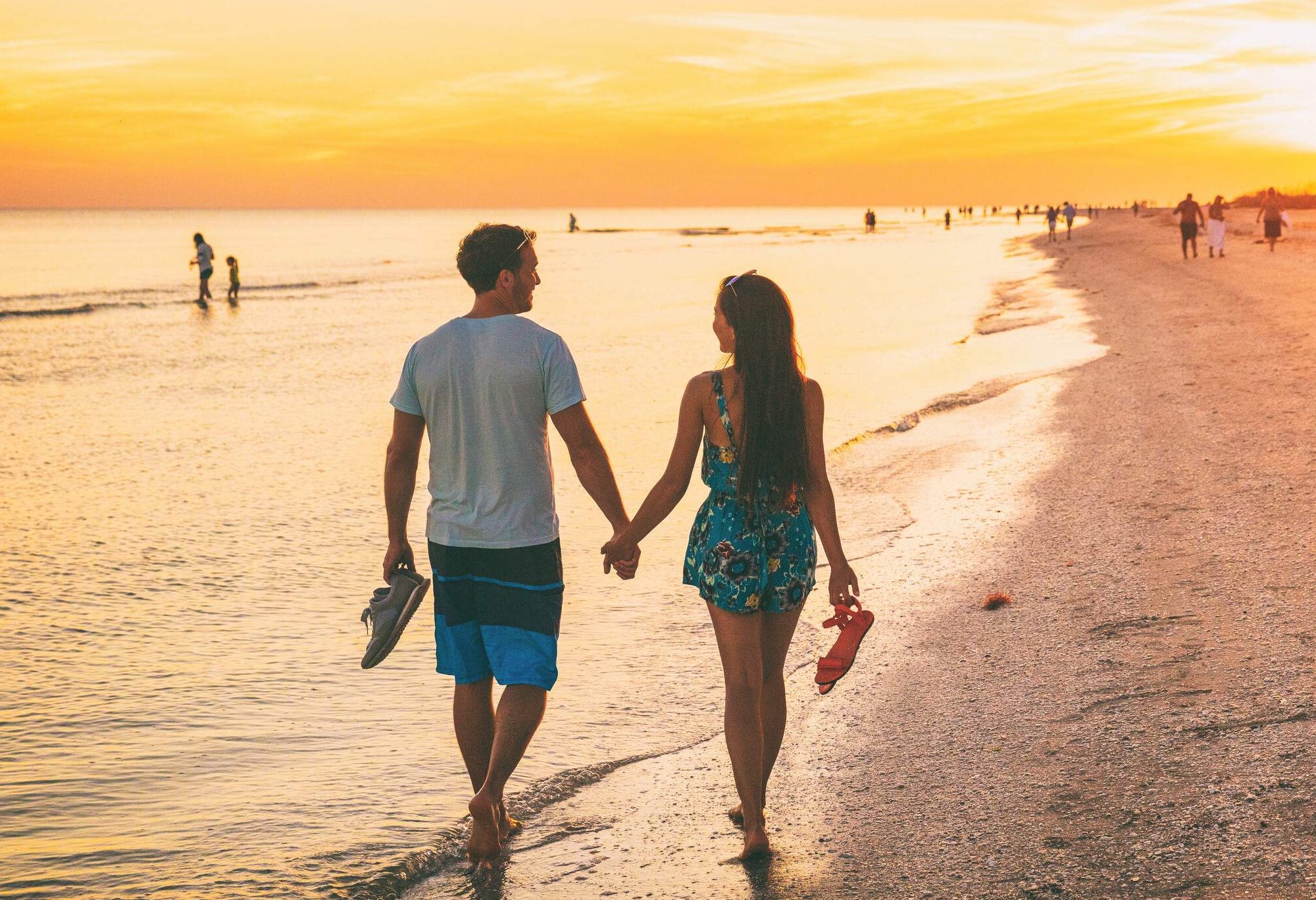 A couple going on a sunset stroll by the beach barefooted.