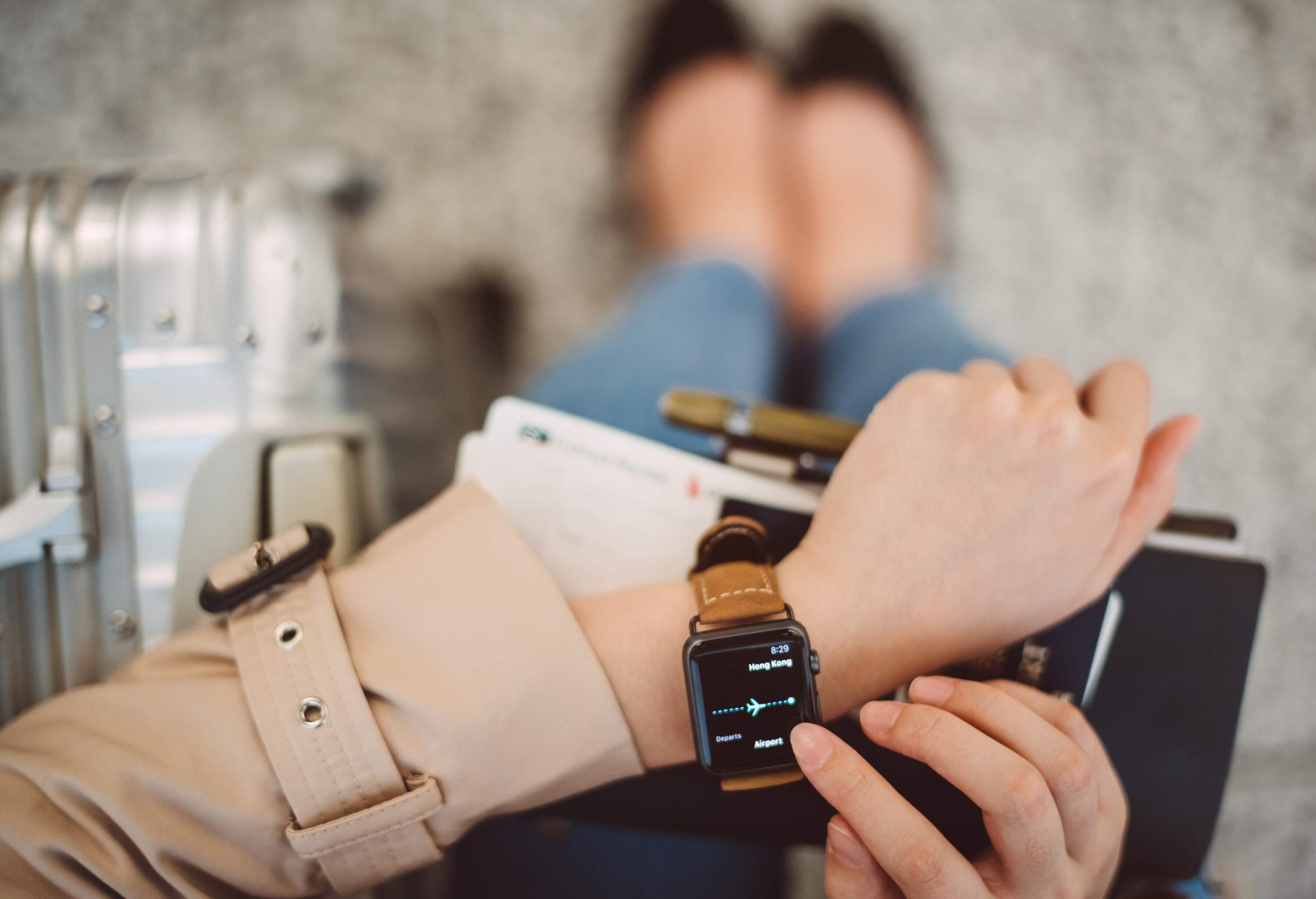 A young lady seamlessly manages her travel plans, glancing at her smartwatch while confidently holding her passport.