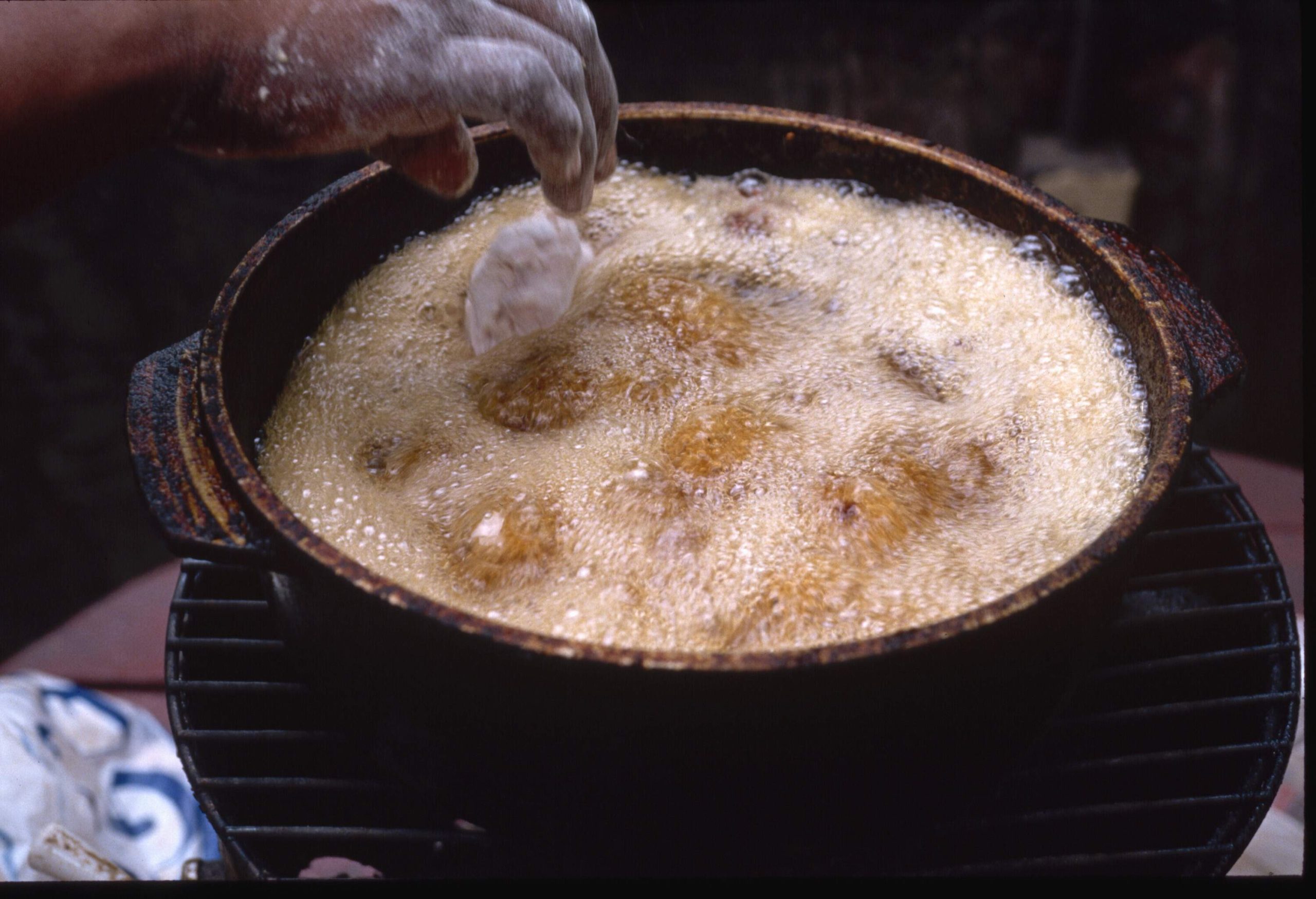 A cook drops conch fritters into hot oil to cook.