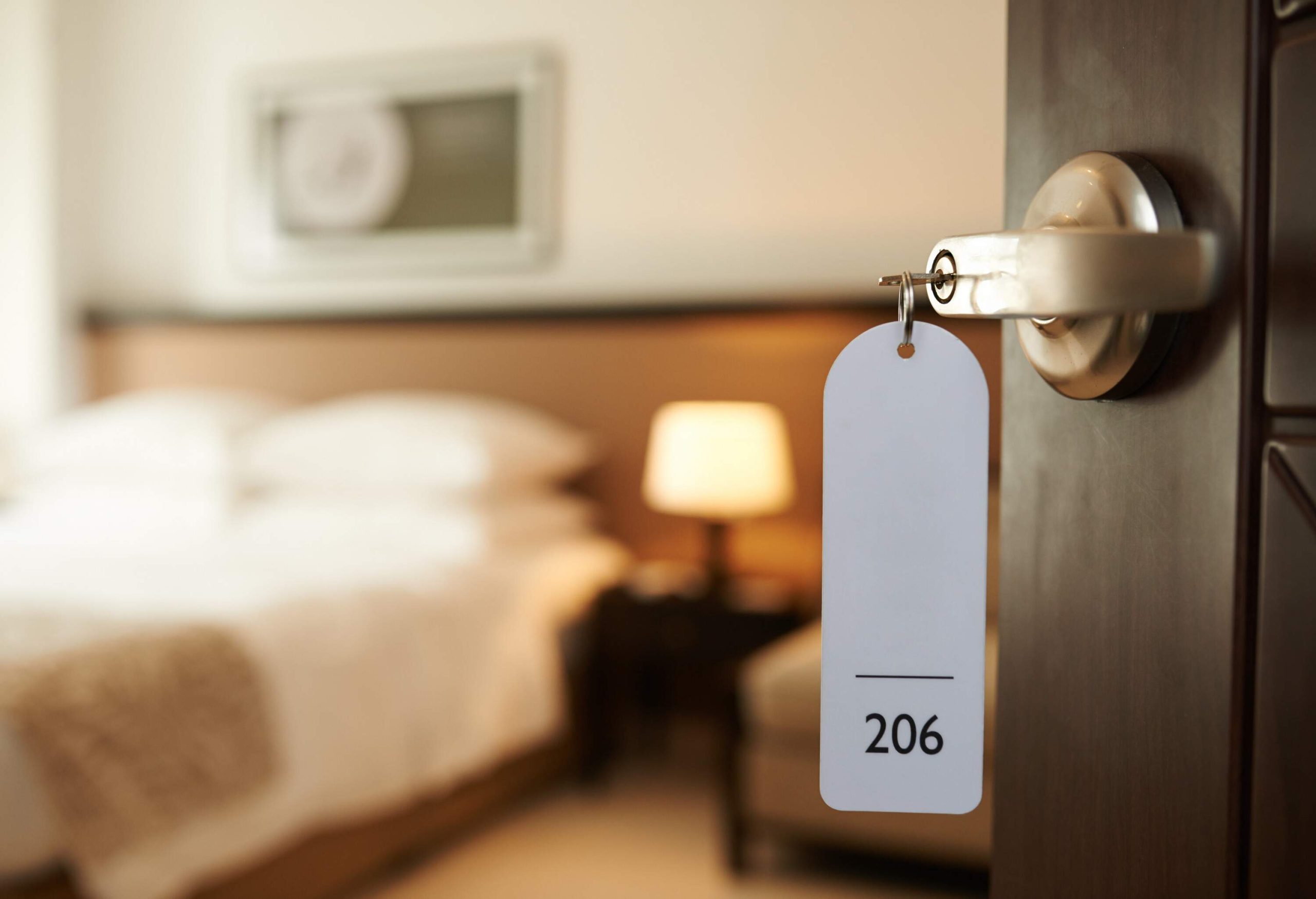 An unlocked hotel room door with the key bearing the number 