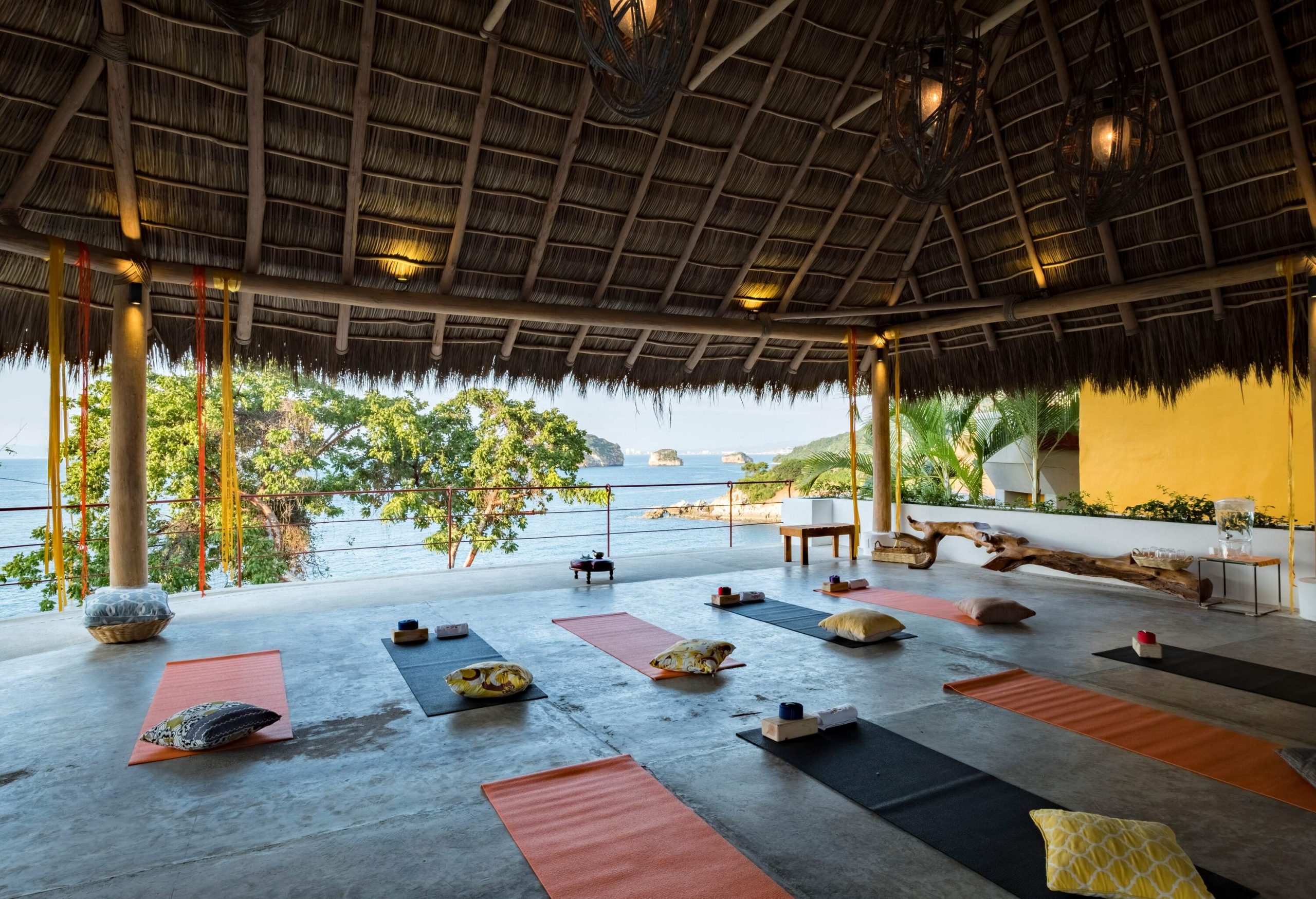 An empty open yoga studio with a thatched roof overlooking the sea.