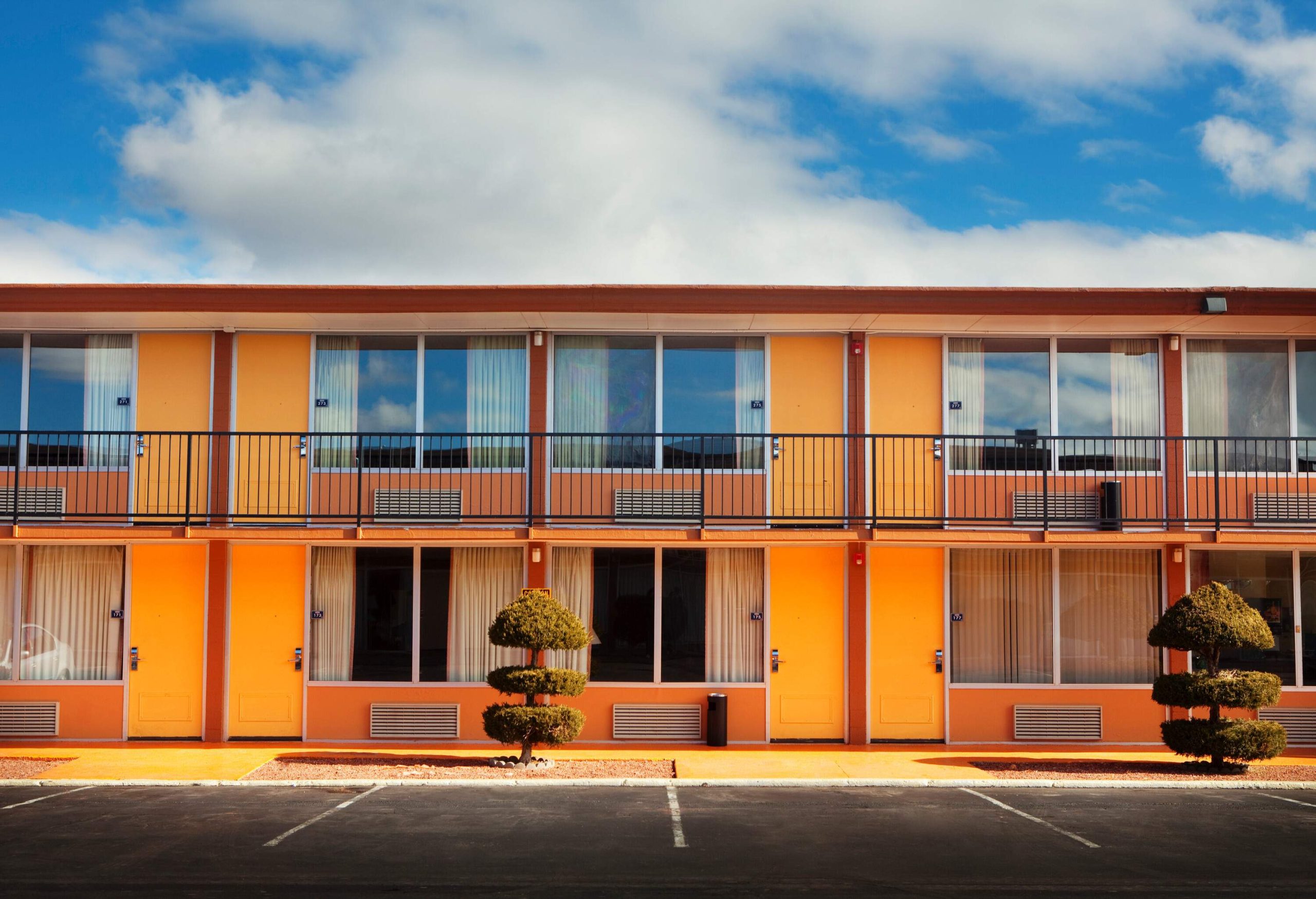 A vibrant motel stands out with its colourful facade, featuring wide glass windows that not only allow abundant natural light to illuminate the interior but also provide a glimpse into the lively atmosphere within.