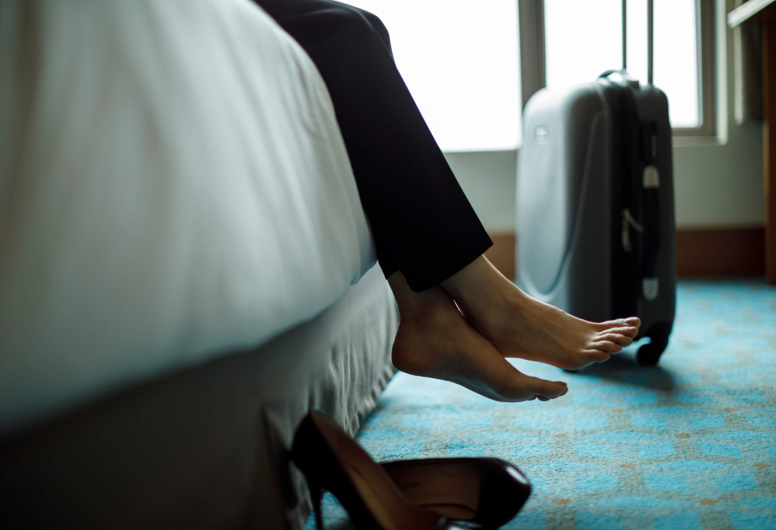 Businesswoman relaxing on bed in a hotel room.