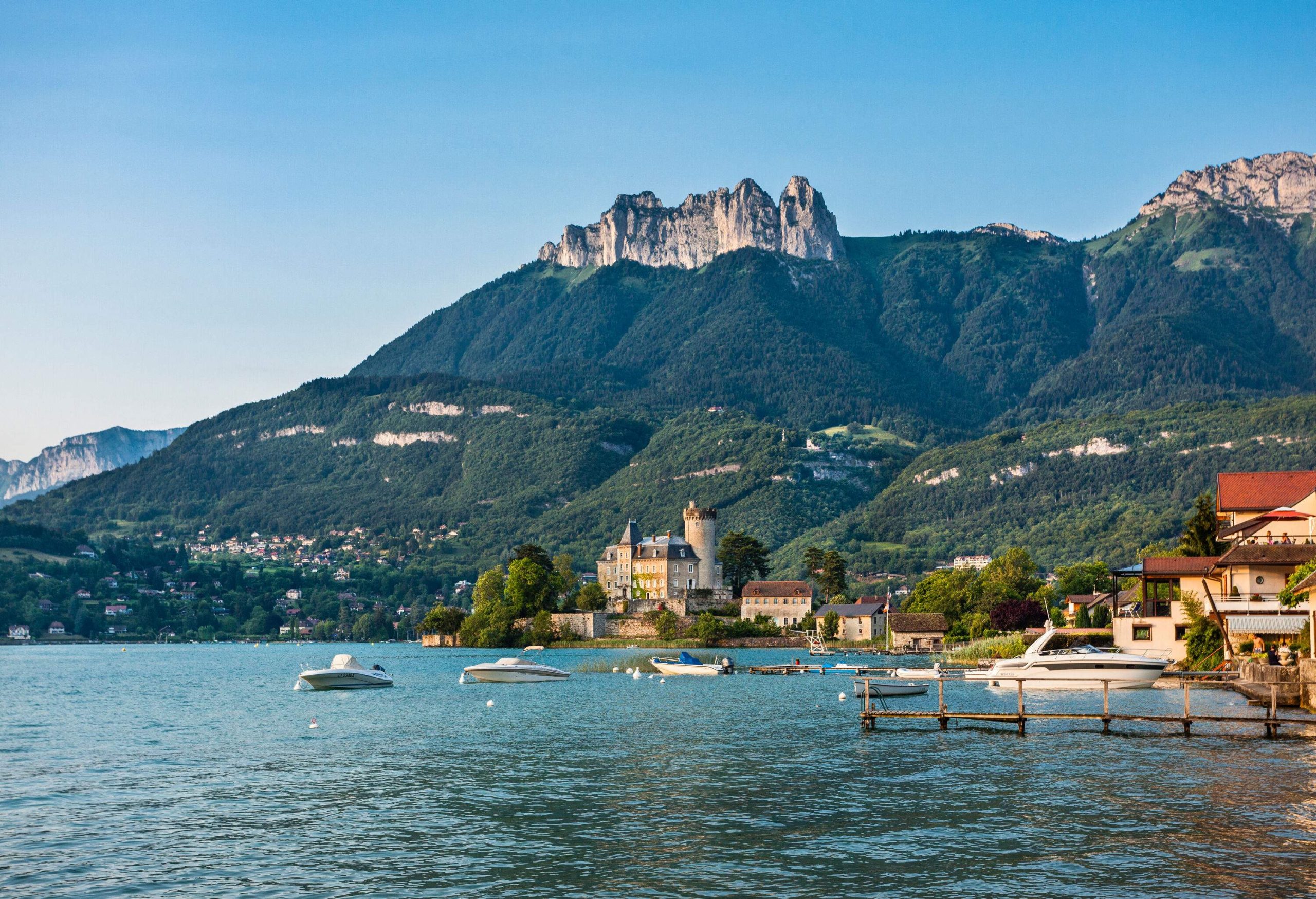 A beautiful village with chateaus beside the lake surrounded by enormous mountains.