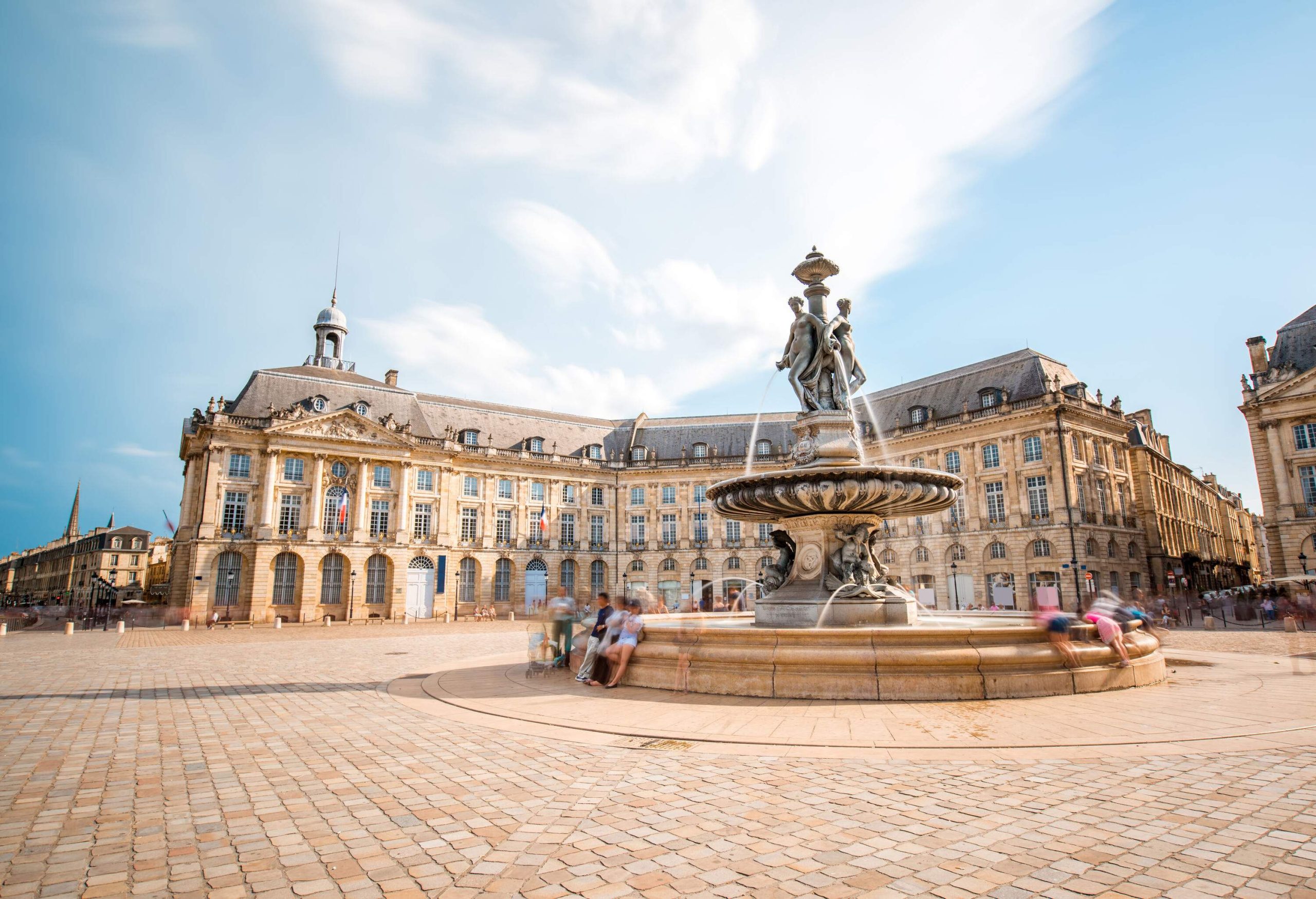 The Three Graces Fountain in the middle of the La Bourse square with the Palais de la Bourse in the background.