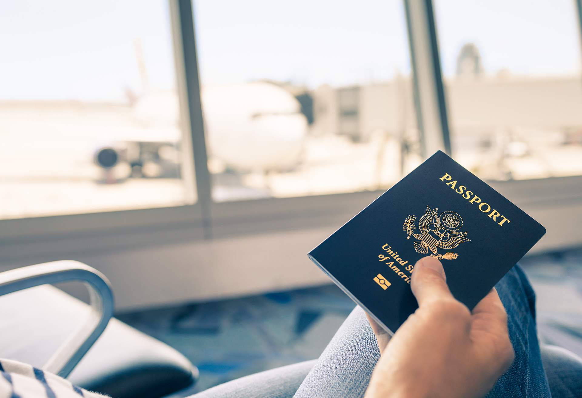 CLOSE UP OF PERSON AT AIRPORT HOLDING US PASSPORT