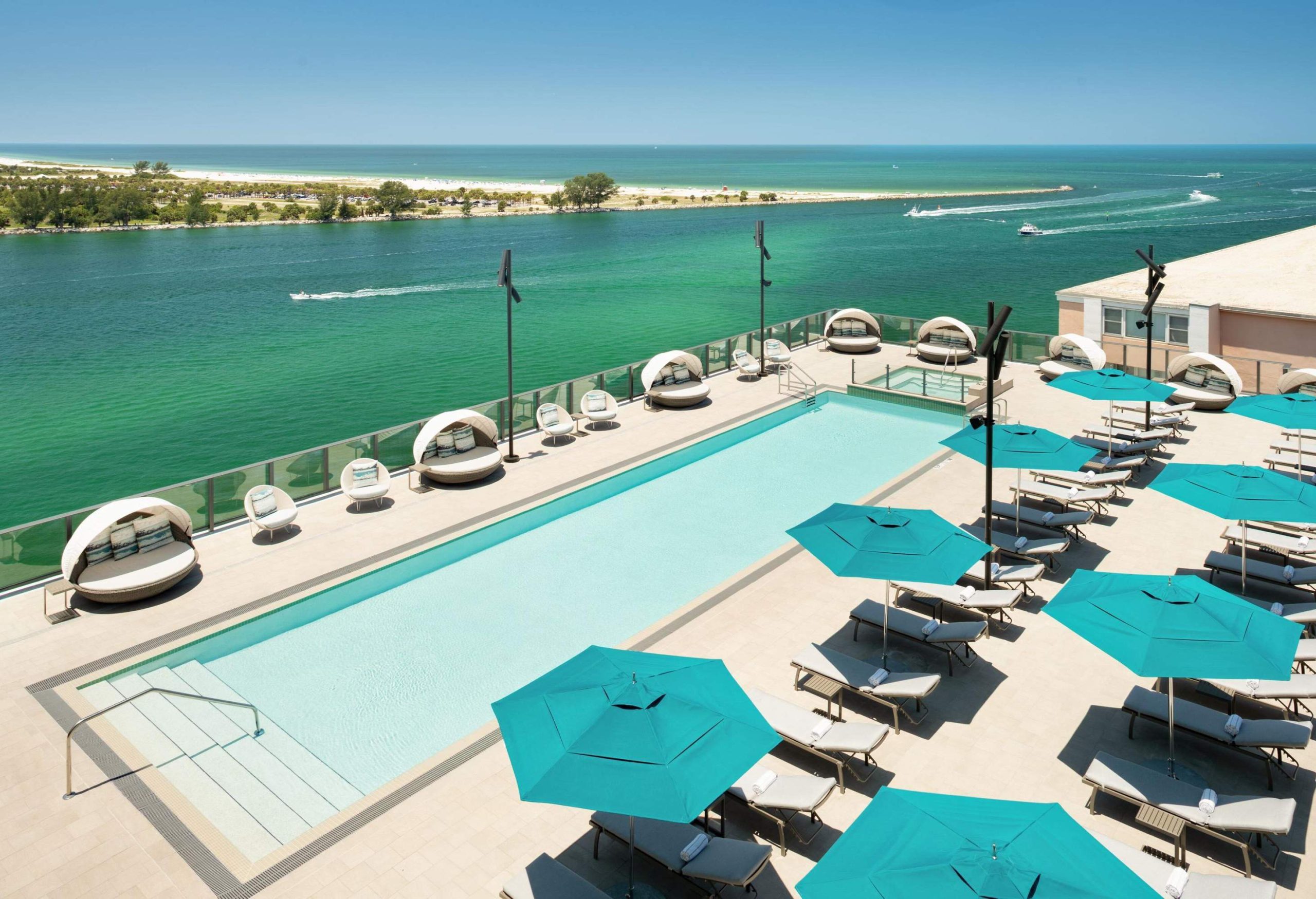 Luxury hotel swimming pool with sun loungers and sun umbrellas overlooking the sea