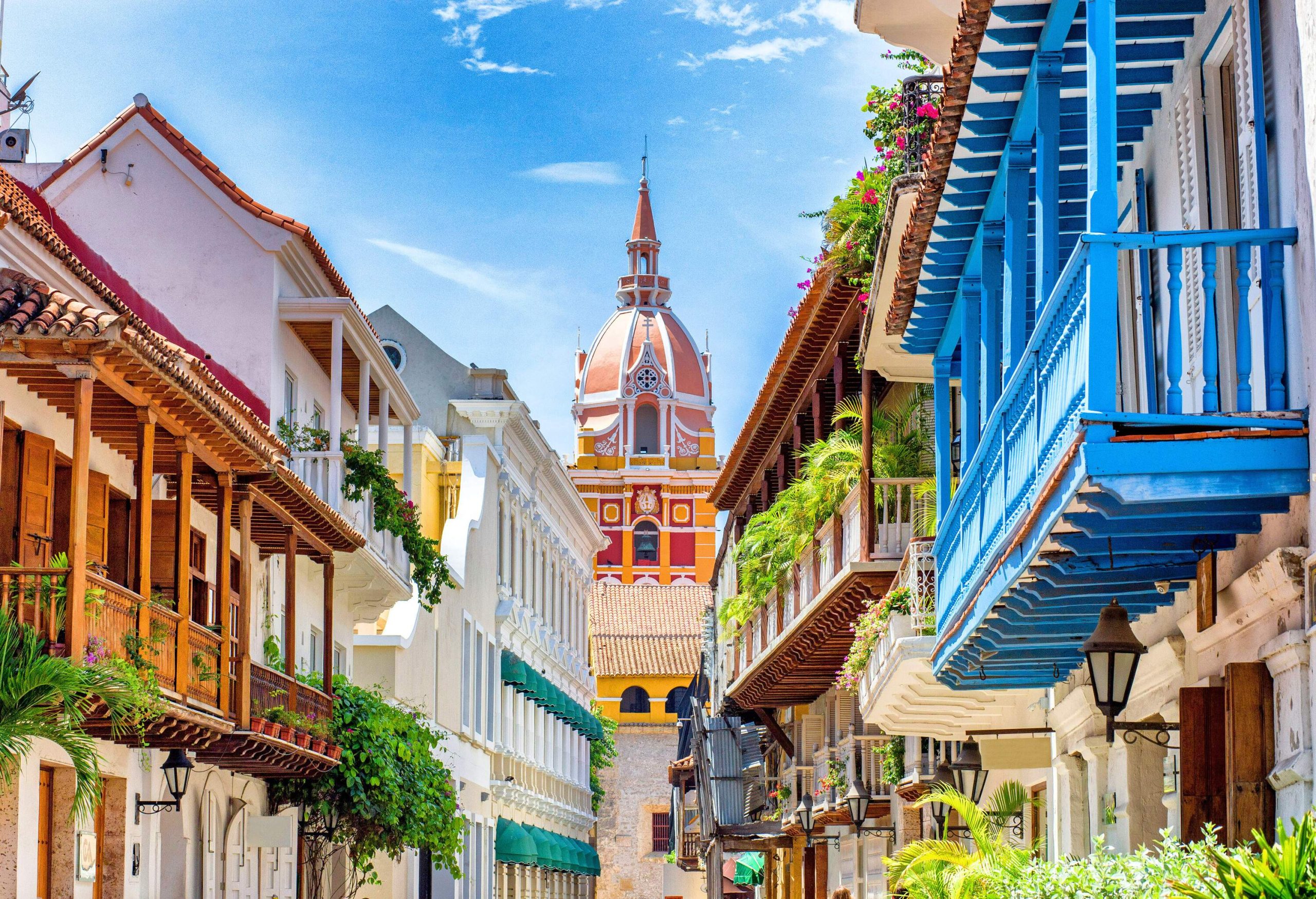 A colourful church dome framed by rows of buildings with large balconies on either side of a street.