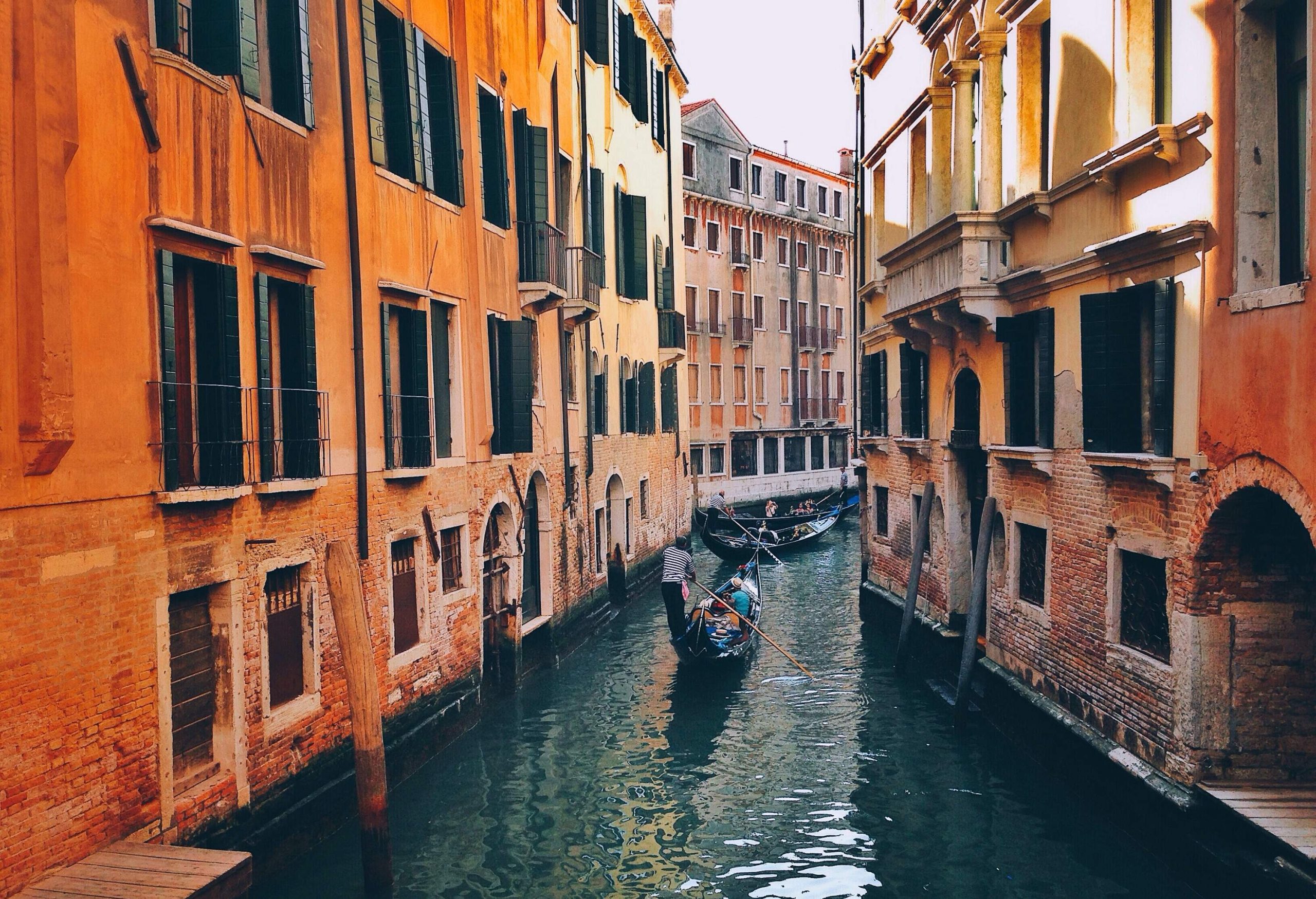 Boats gracefully glide along a serene canal, embraced by buildings on either side.