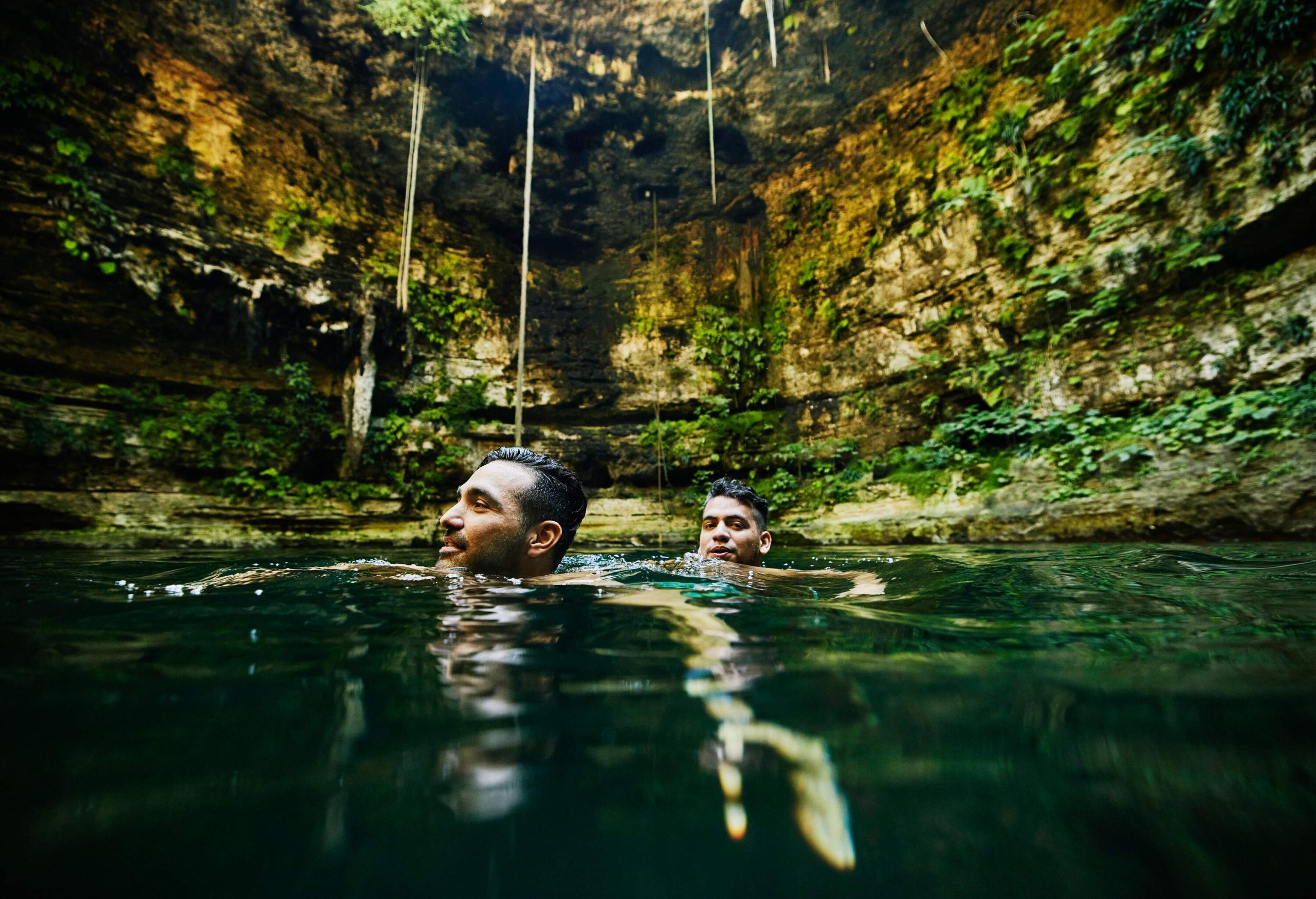 Two males submerged in the waters of a natural cave.